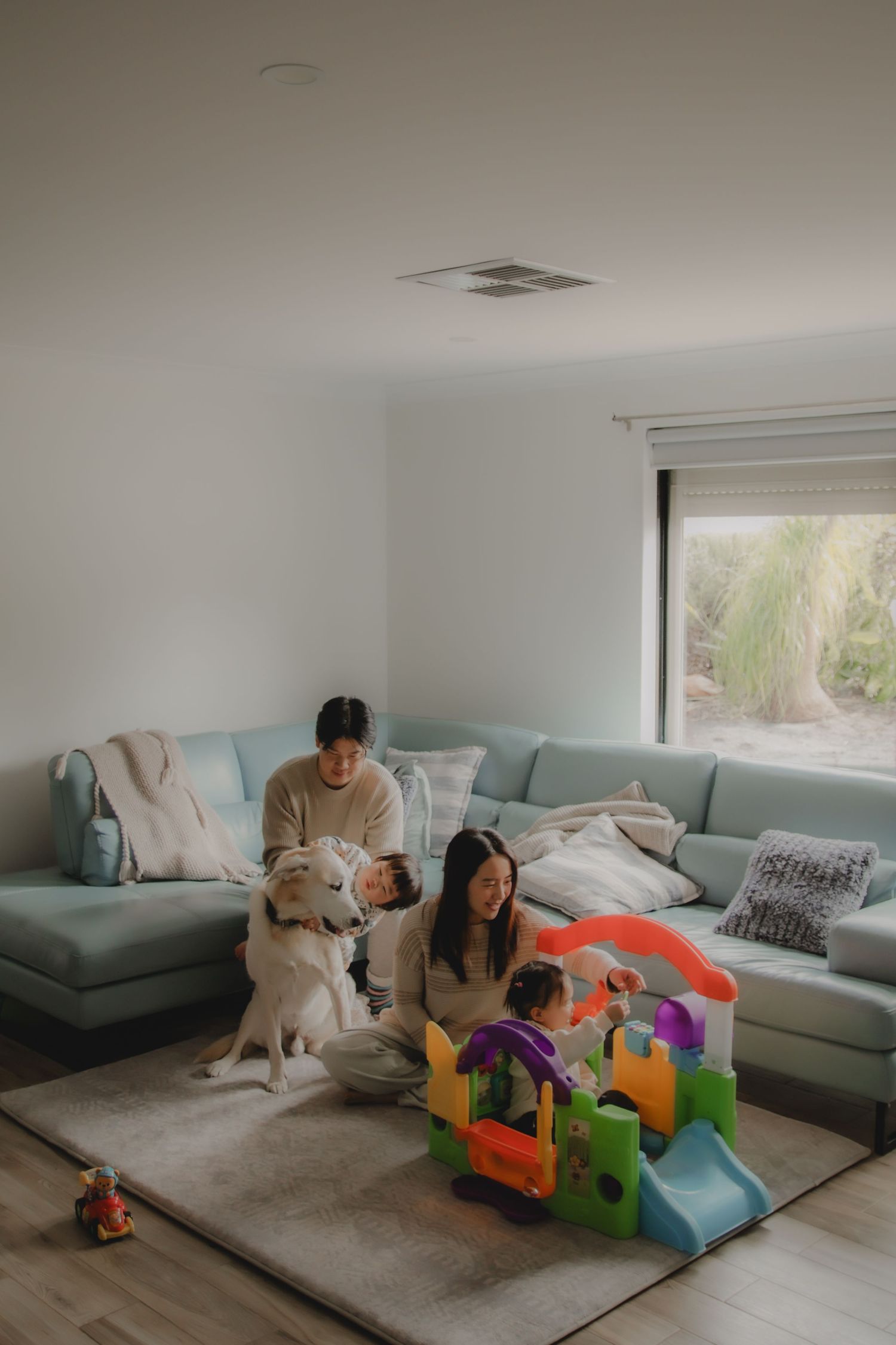 In-home family photoshoot in Singapore capturing candid moments between parents and children at home, with pet dog