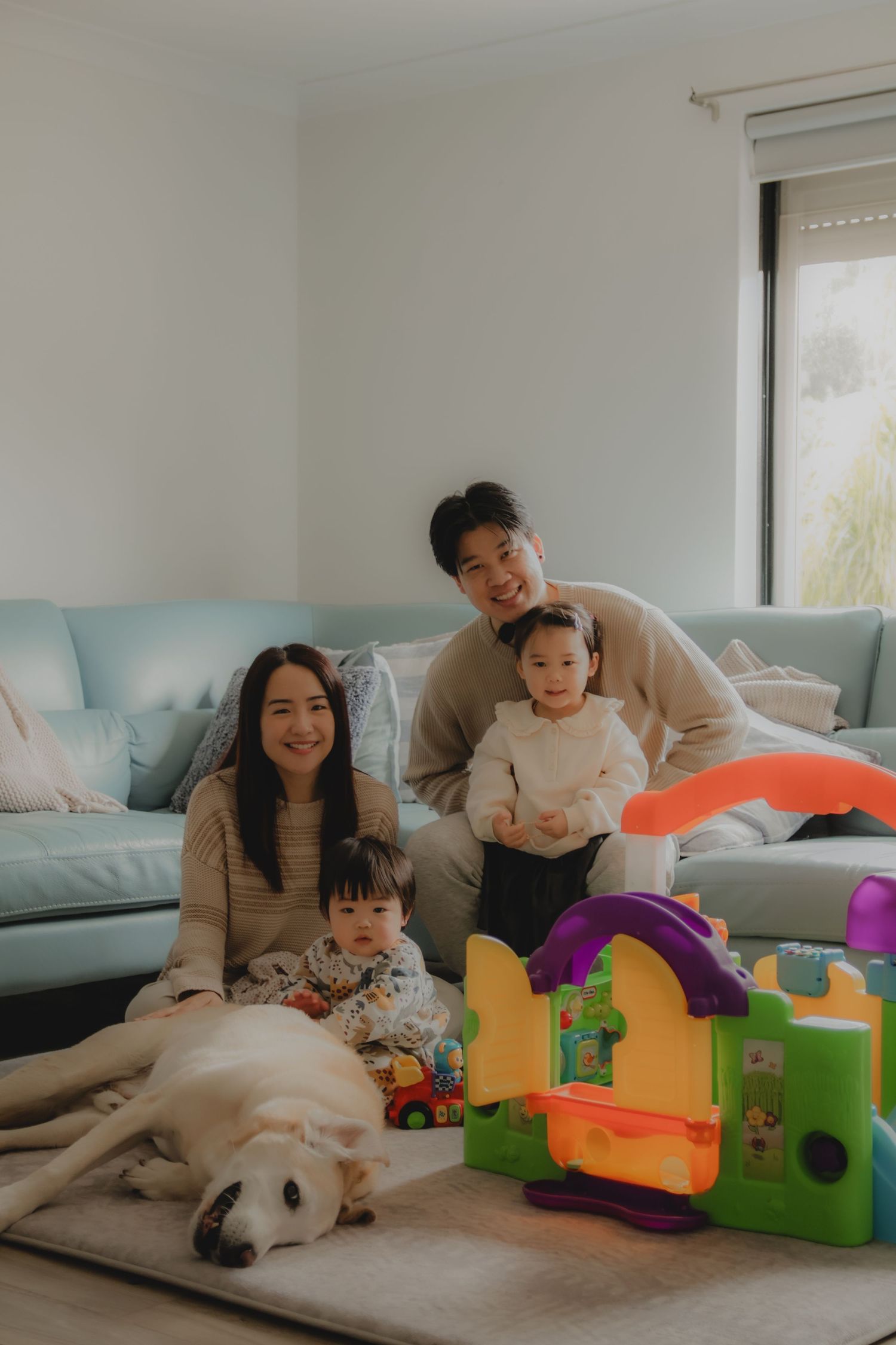 In-home family photoshoot in Singapore capturing candid moments between parents and children at home, with pet dog