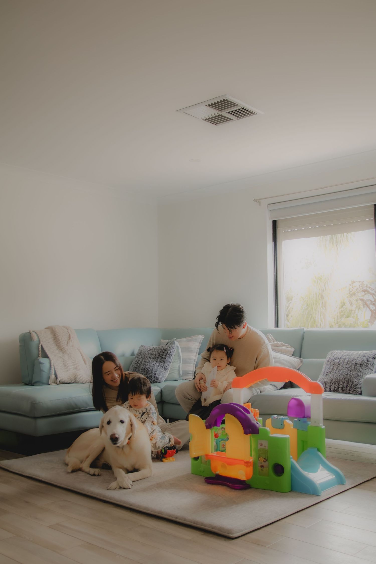 In-home family photoshoot in Singapore capturing candid moments between parents and children at home, with pet dog