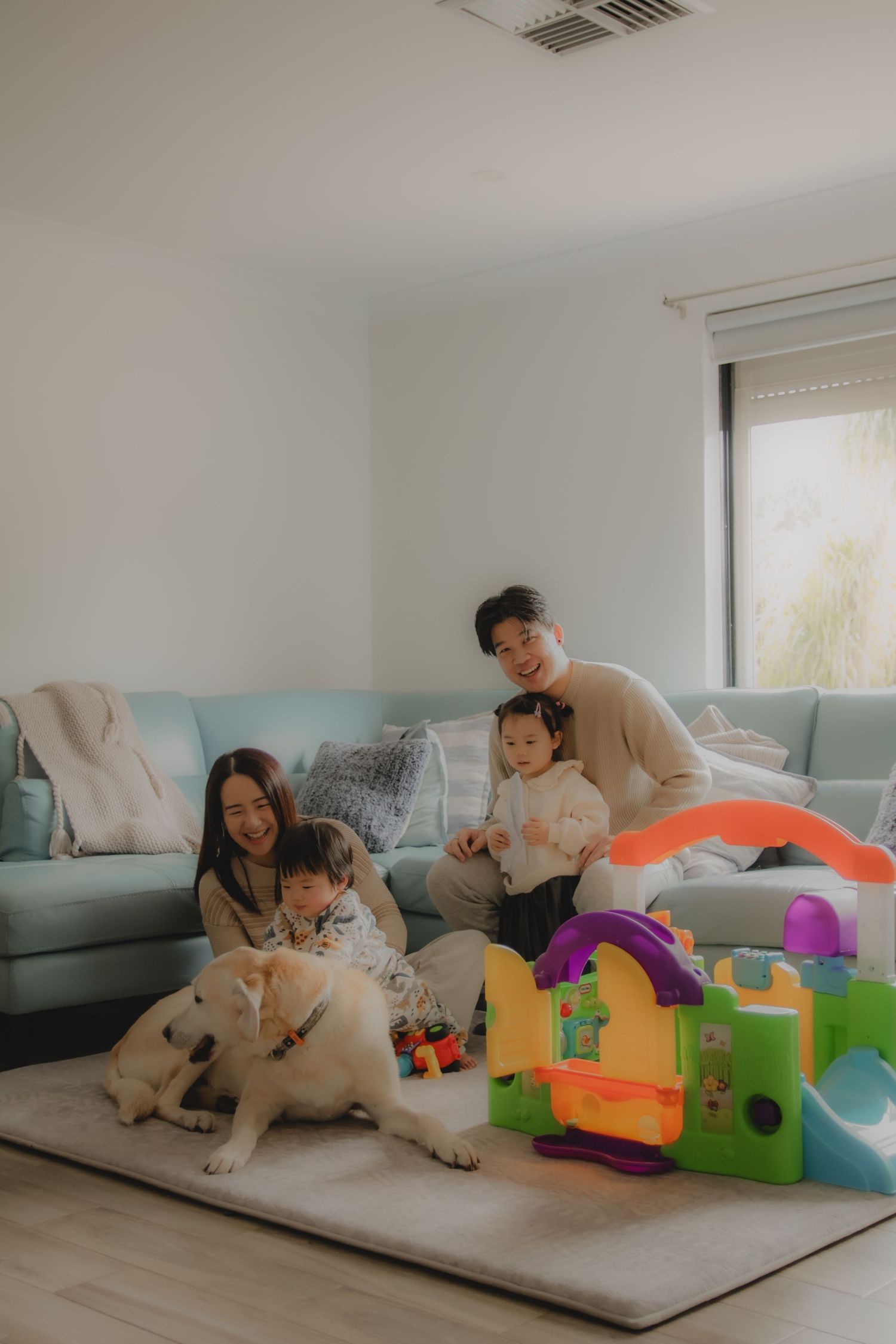 In-home family photoshoot in Singapore capturing candid moments between parents and children at home, with pet dog