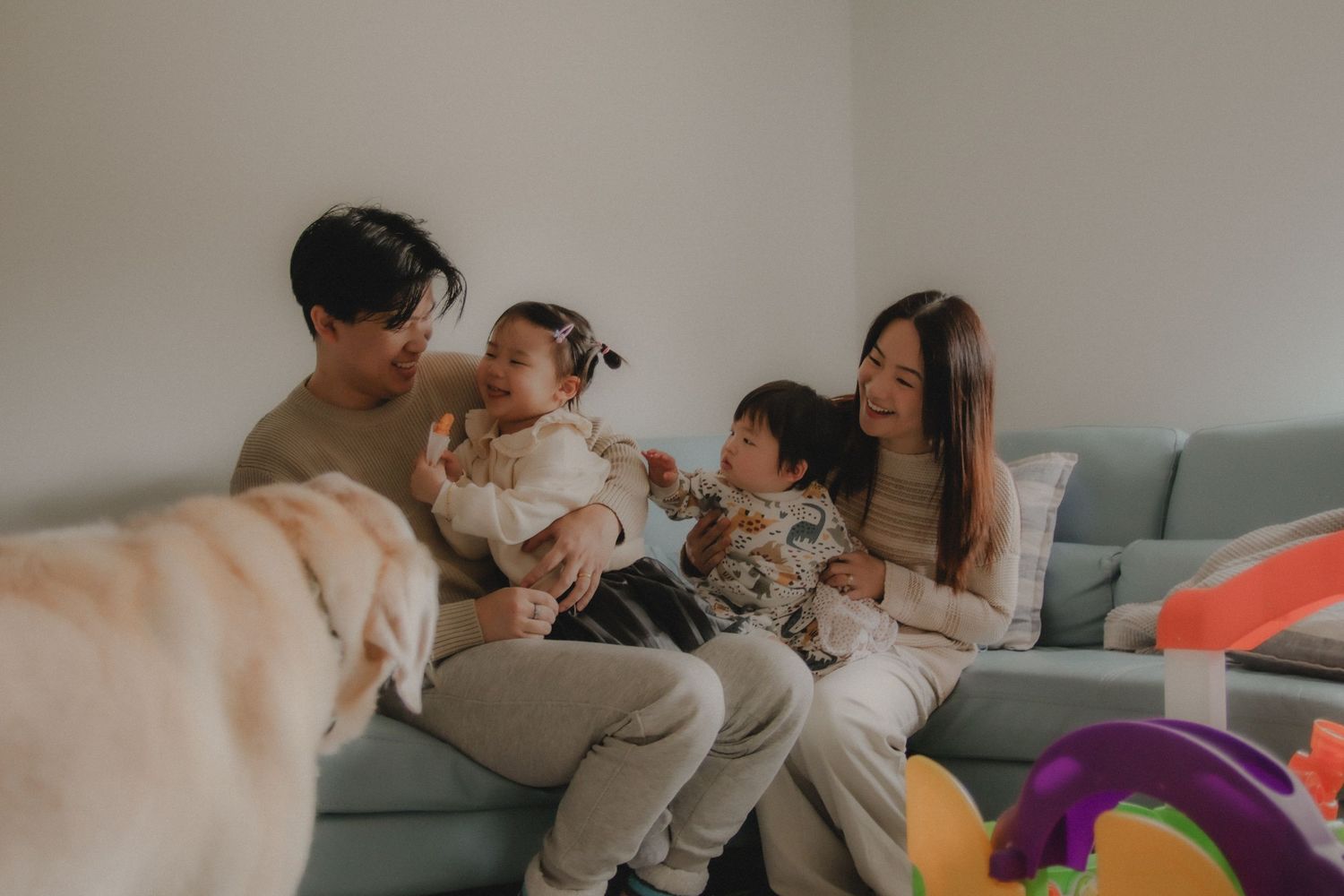 In-home family photoshoot in Singapore capturing candid moments between parents and children at home, with pet dog