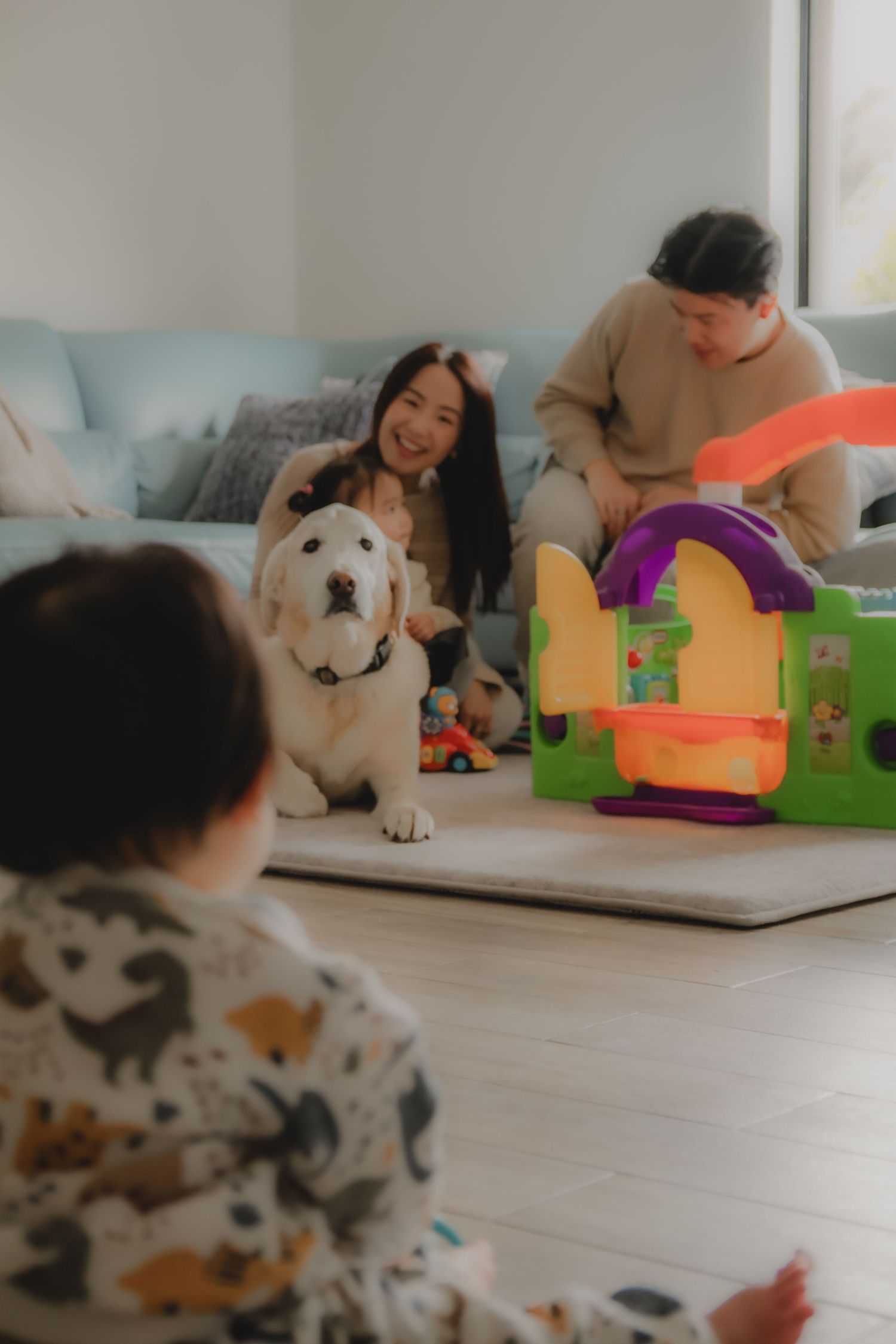 In-home family photoshoot in Singapore capturing candid moments between parents and children at home, with pet dog