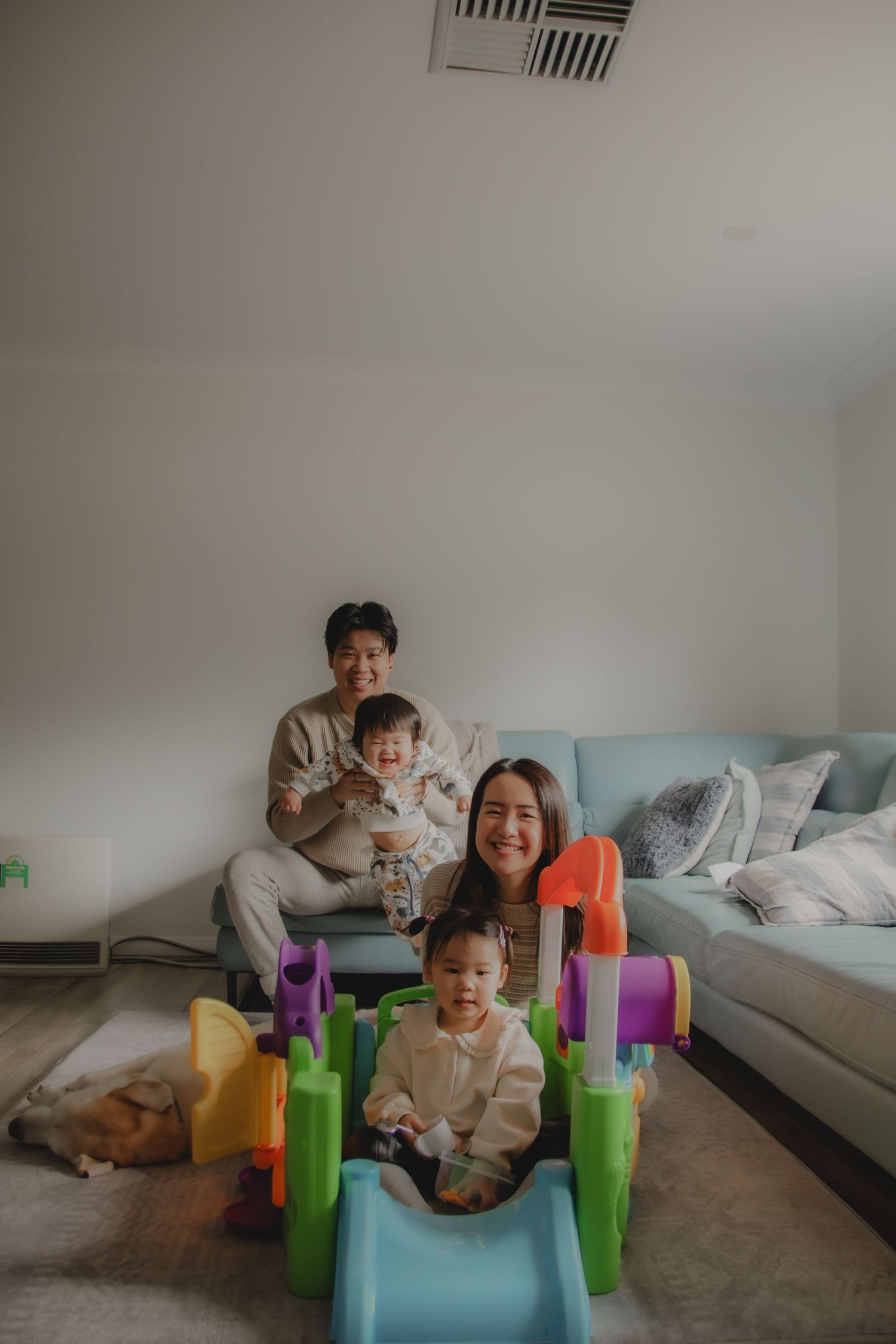 In-home family photoshoot in Singapore capturing candid moments between parents and children at home, with pet dog