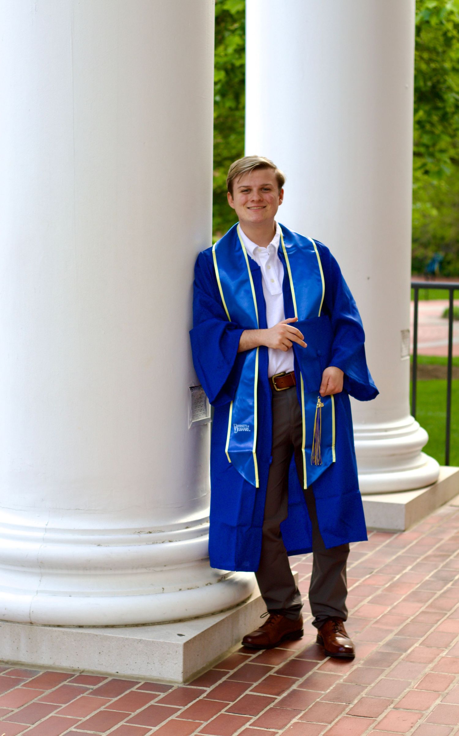 portrait of male graduate from the university of Delaware in graduate regalia at memorial hall