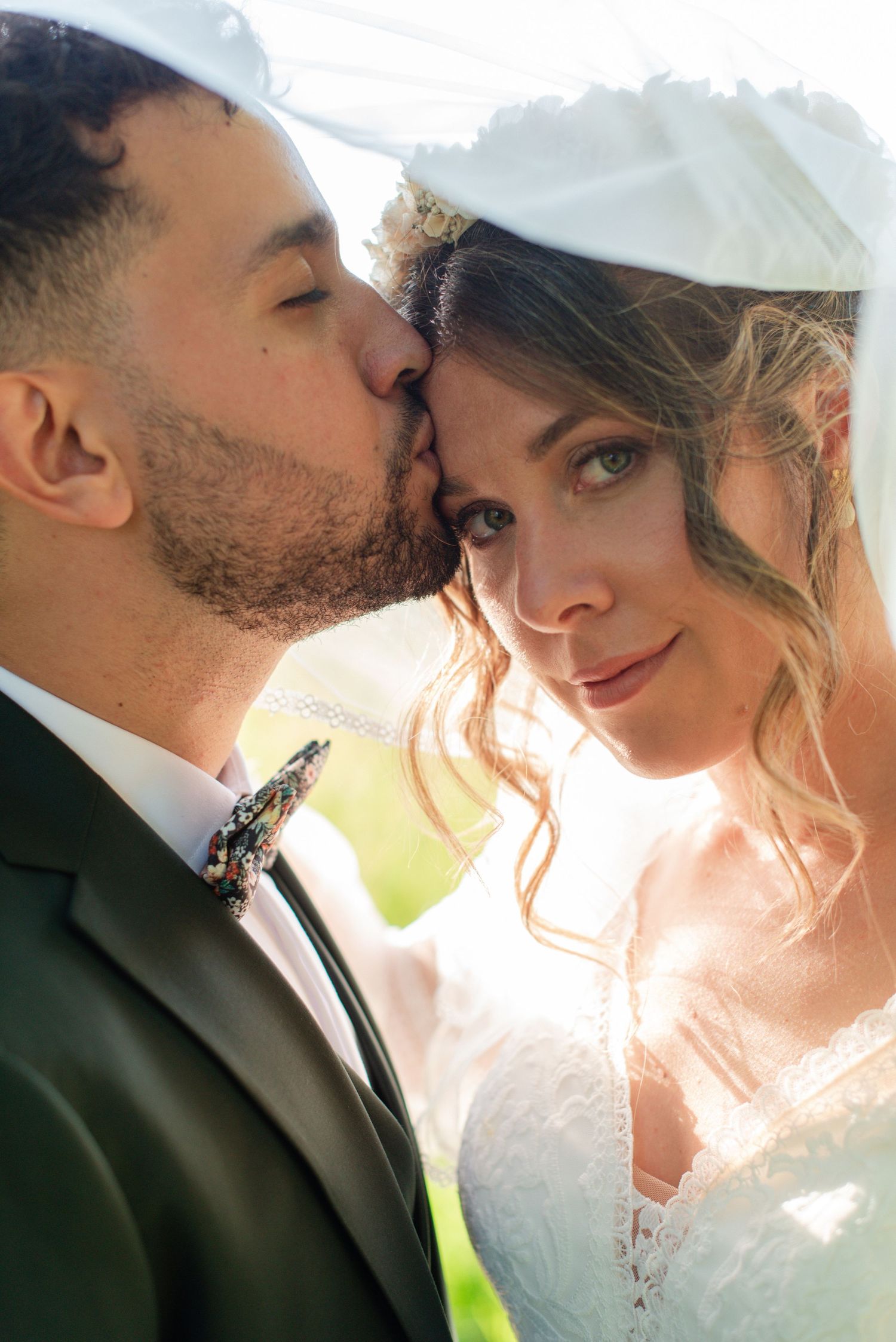 couple de jeunes mariés pendant leur shooting couple, la photo est realisée sous le voile de la mariée