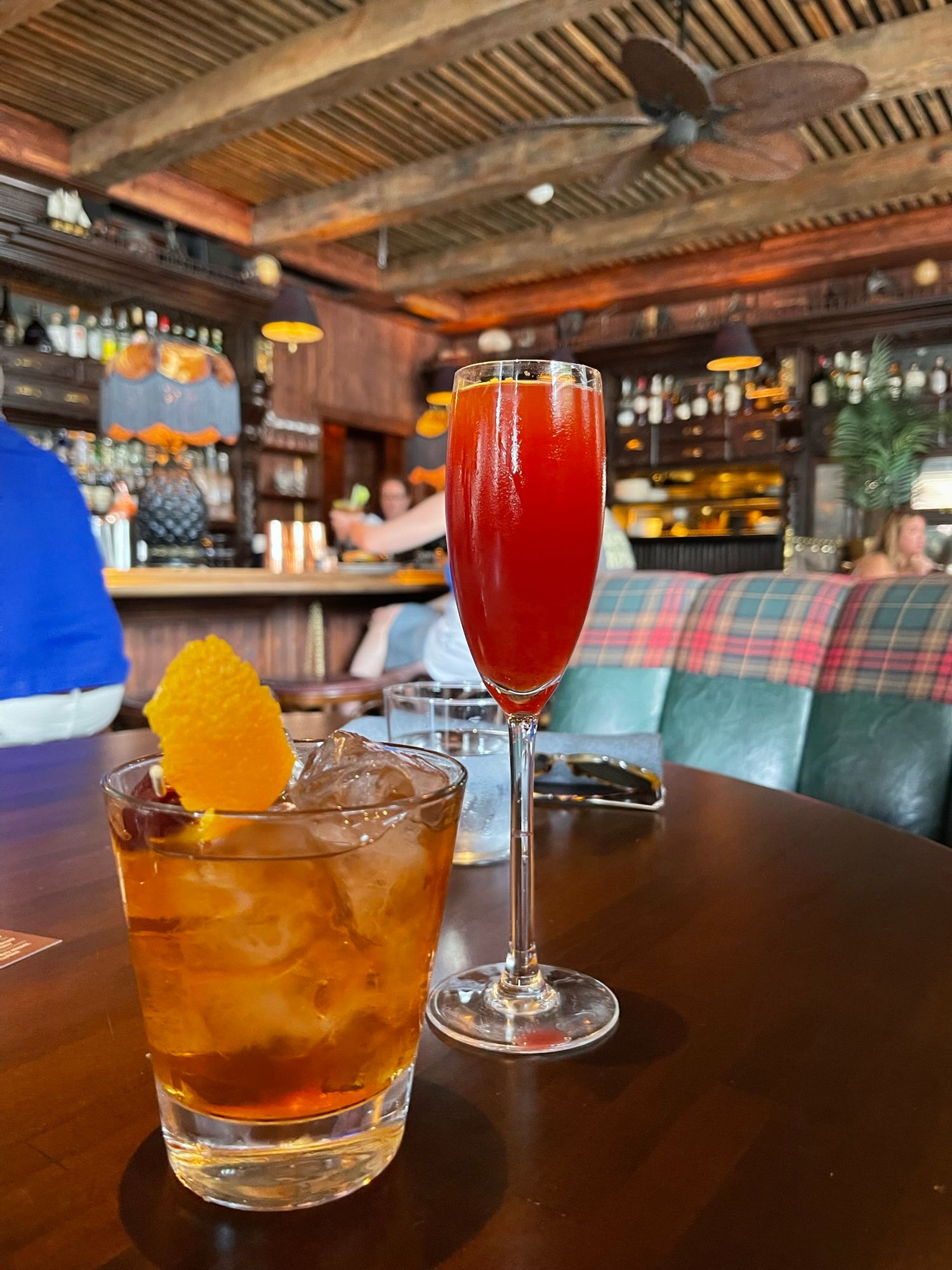 Two cocktails on a wooden bar table, an old fashioned with orange peel and a red Bellini in a flute glass | Sydney Allen Photography