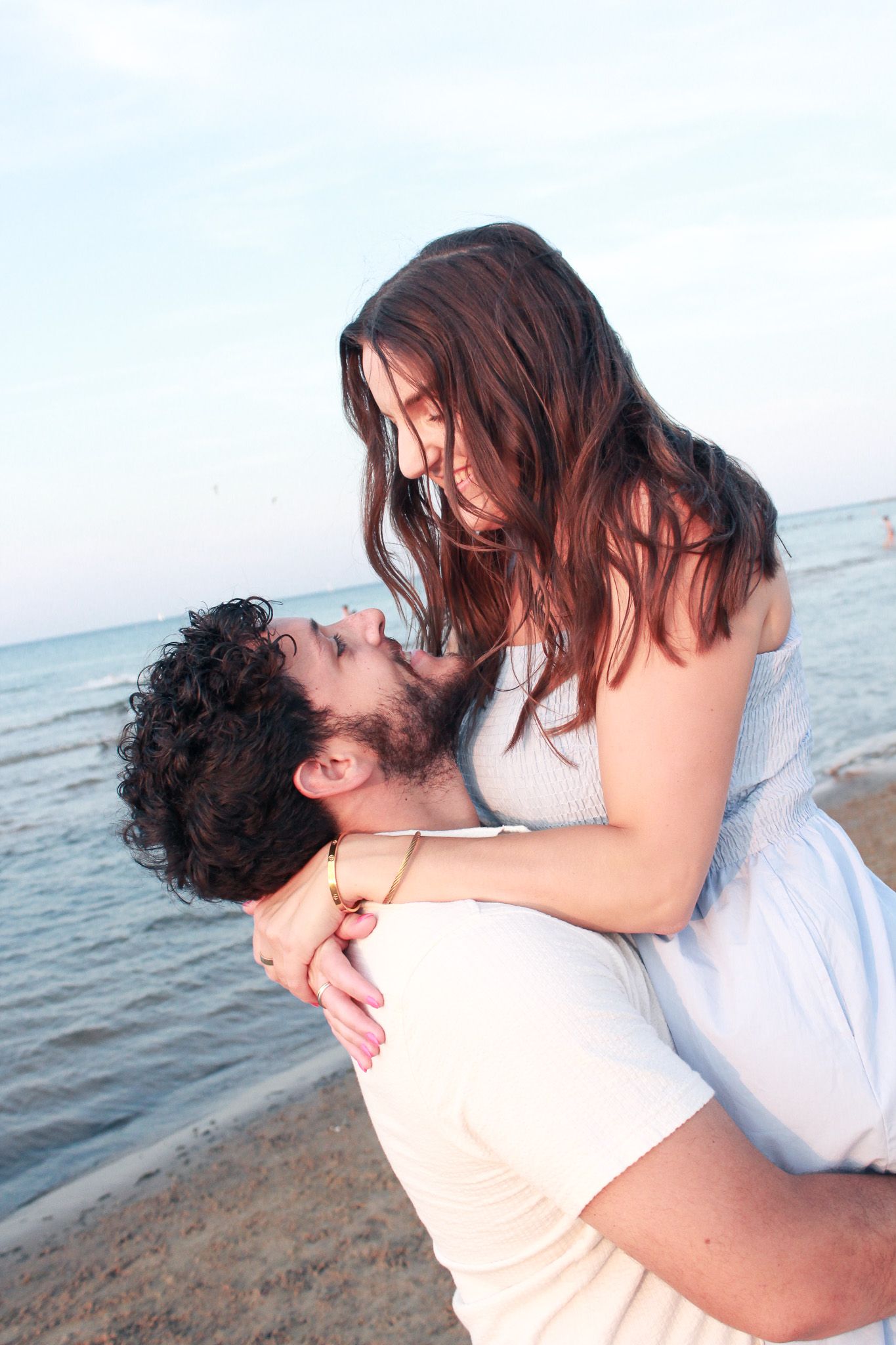A romantic couple embraces and kisses on Montrose beach with ocean waves in the background | Sydney Allen Photography