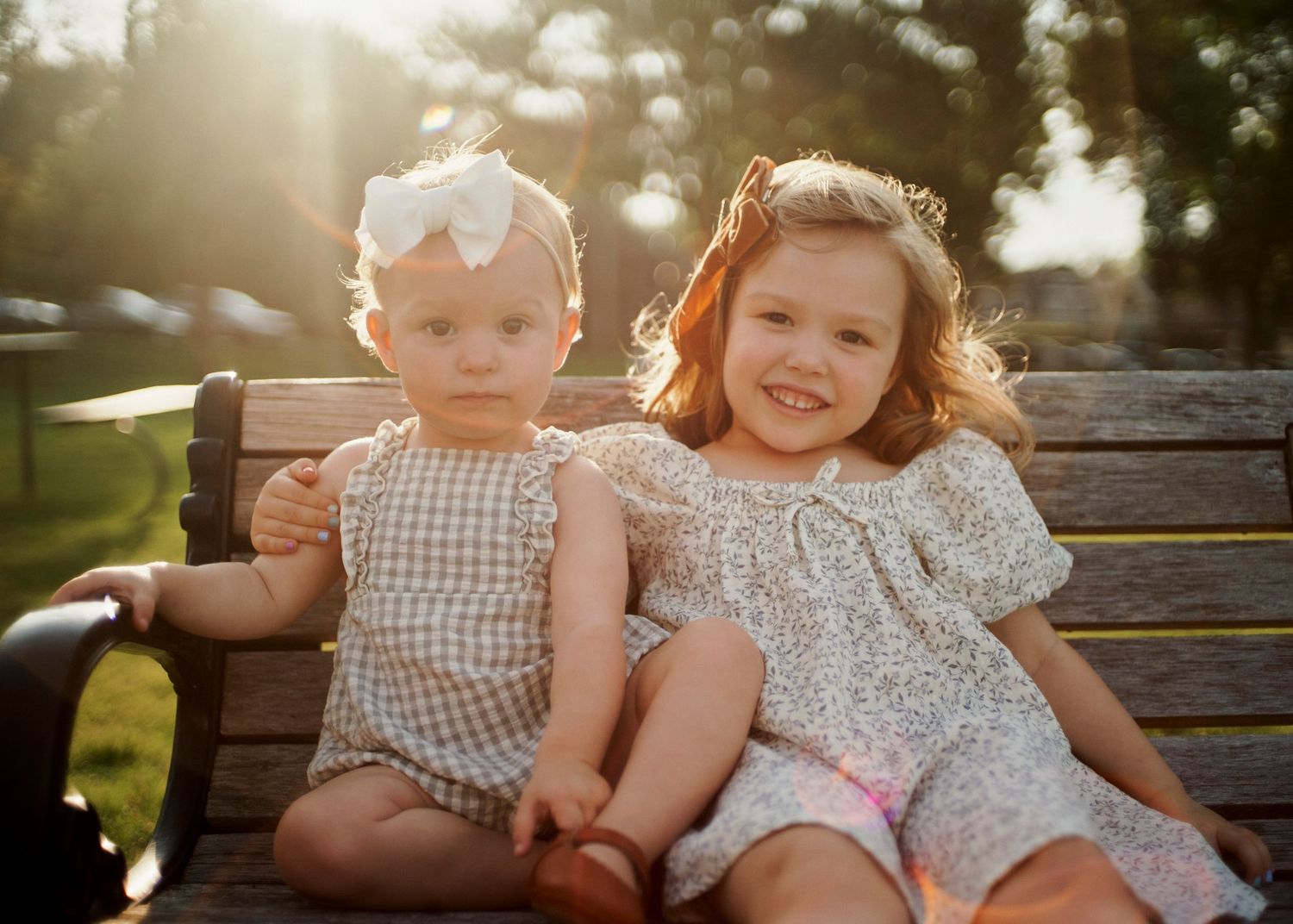 Siblings share a sweet moment on park bench at sunset.