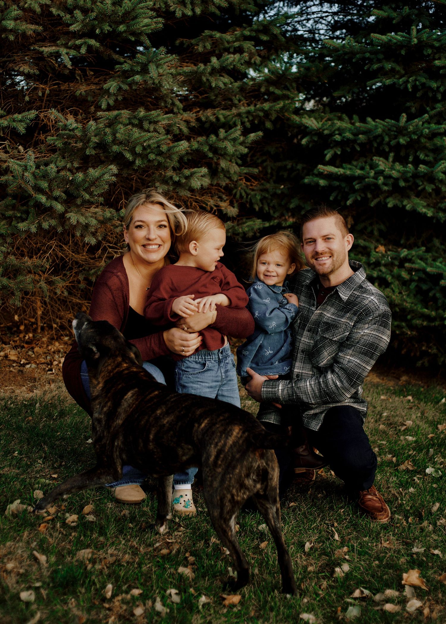 Family group sitting together on fallen autumn leaves with their dog.