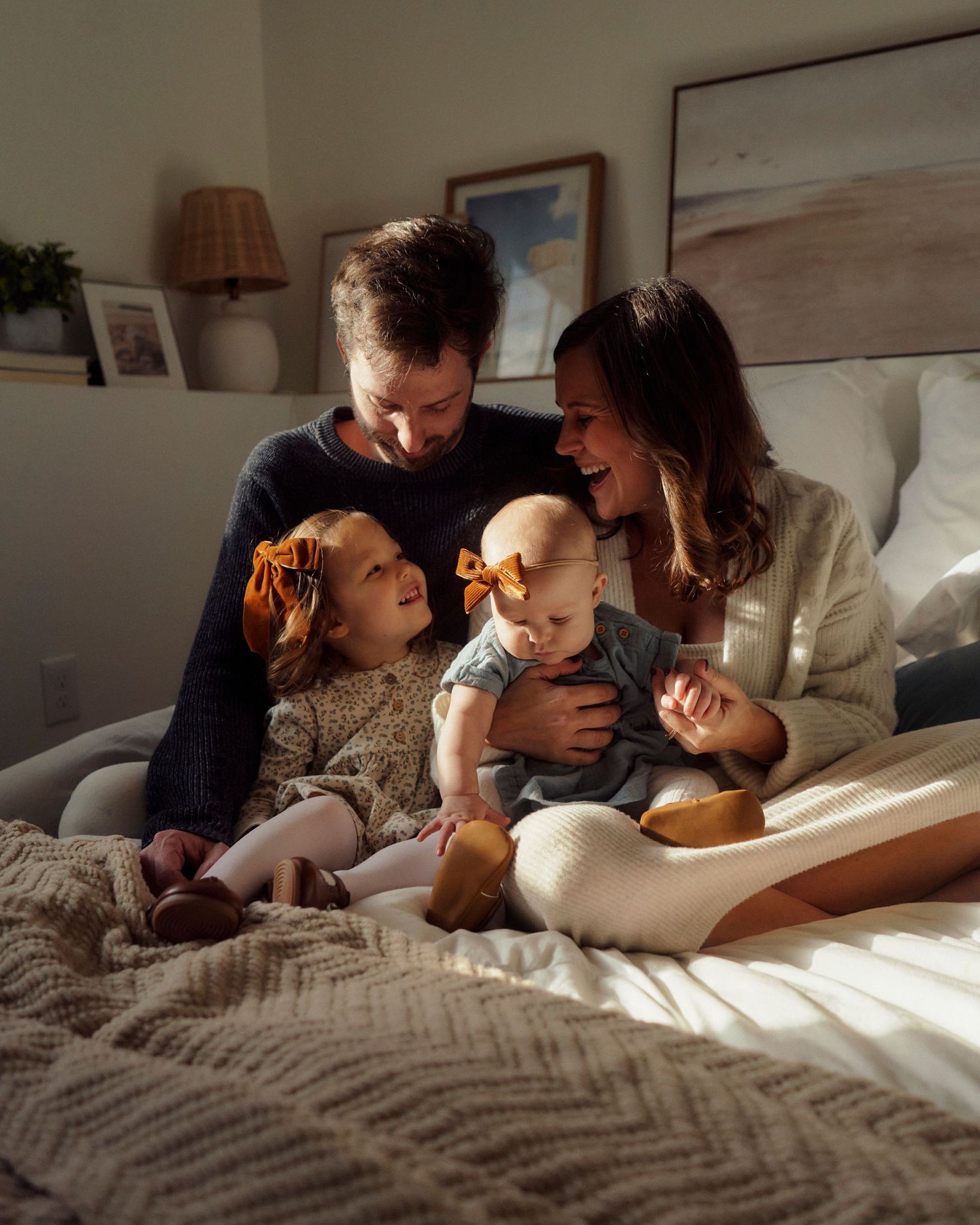 Intimate couple sharing tender moments together while relaxing in bed with natural sunlight streaming through window.