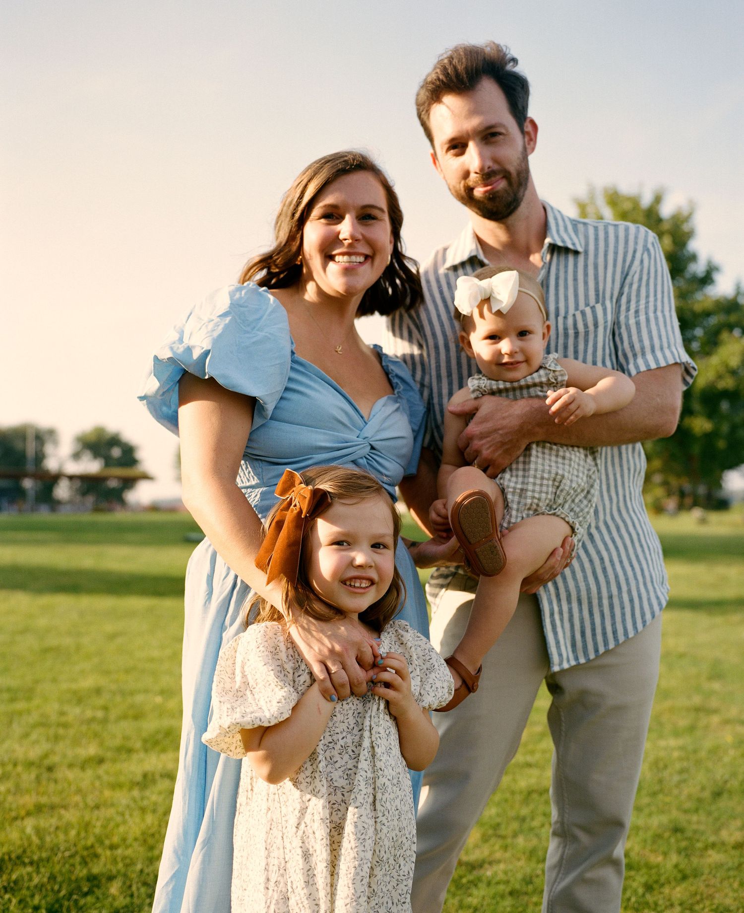 A family shares laughter and embraces during a sunset photo session in the park.