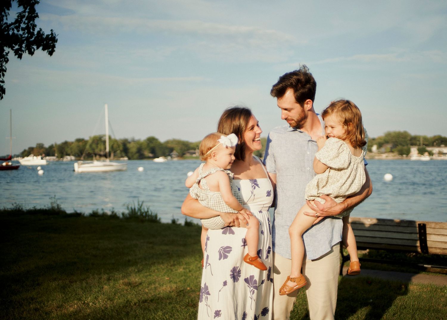Family portrait session by a waterfront with sailboats in the background.