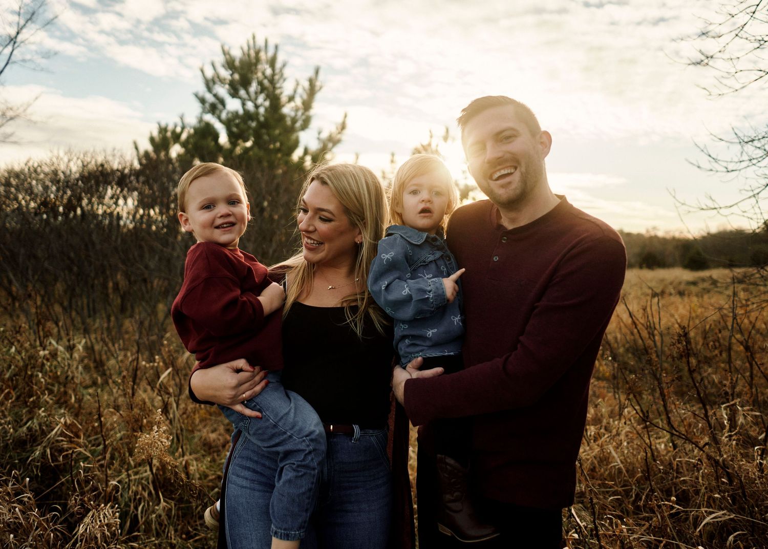 Sunset family photoshoot in a golden field with warm autumn colors.