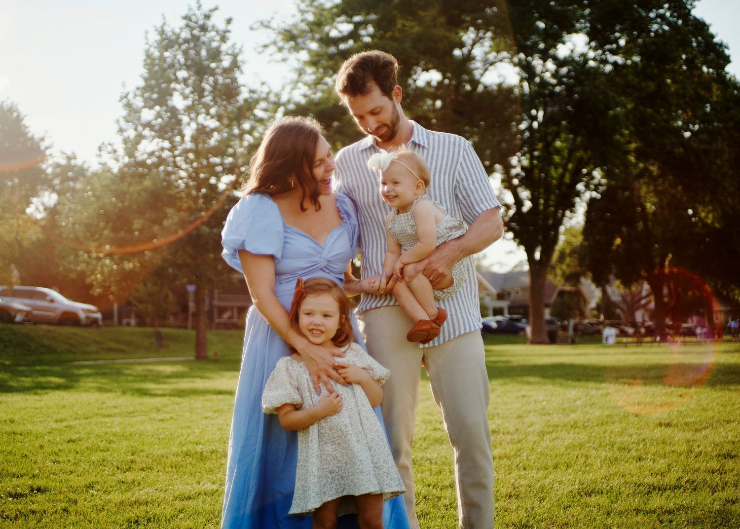 A family plays together on green grass during a warm summer evening.