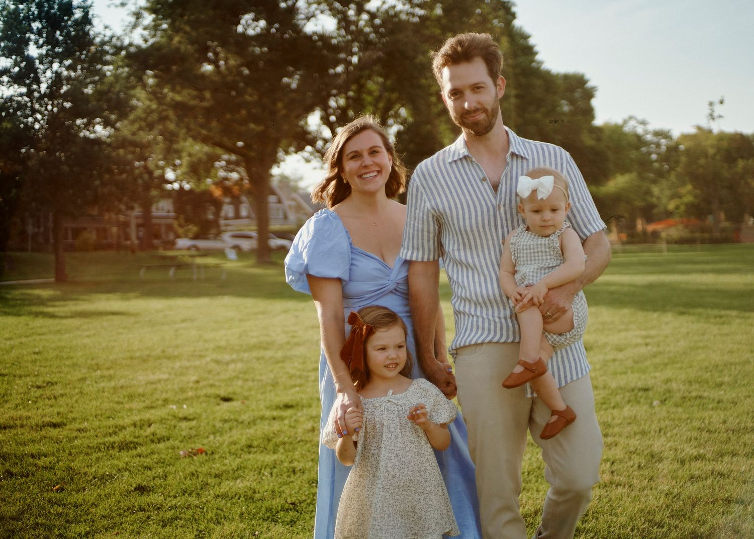 A family shares joyful moments together in a sunny park setting.