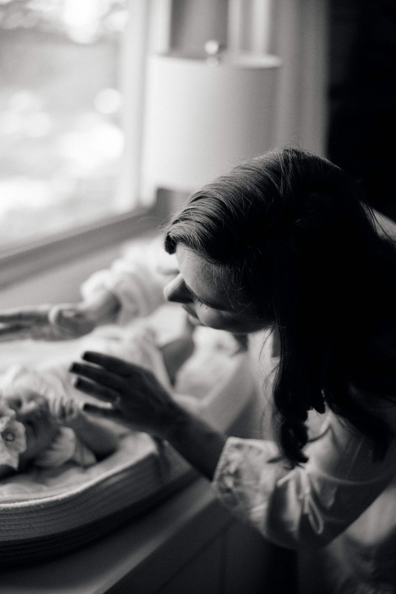 Black and white image of someone looking down at a dining table near a window.