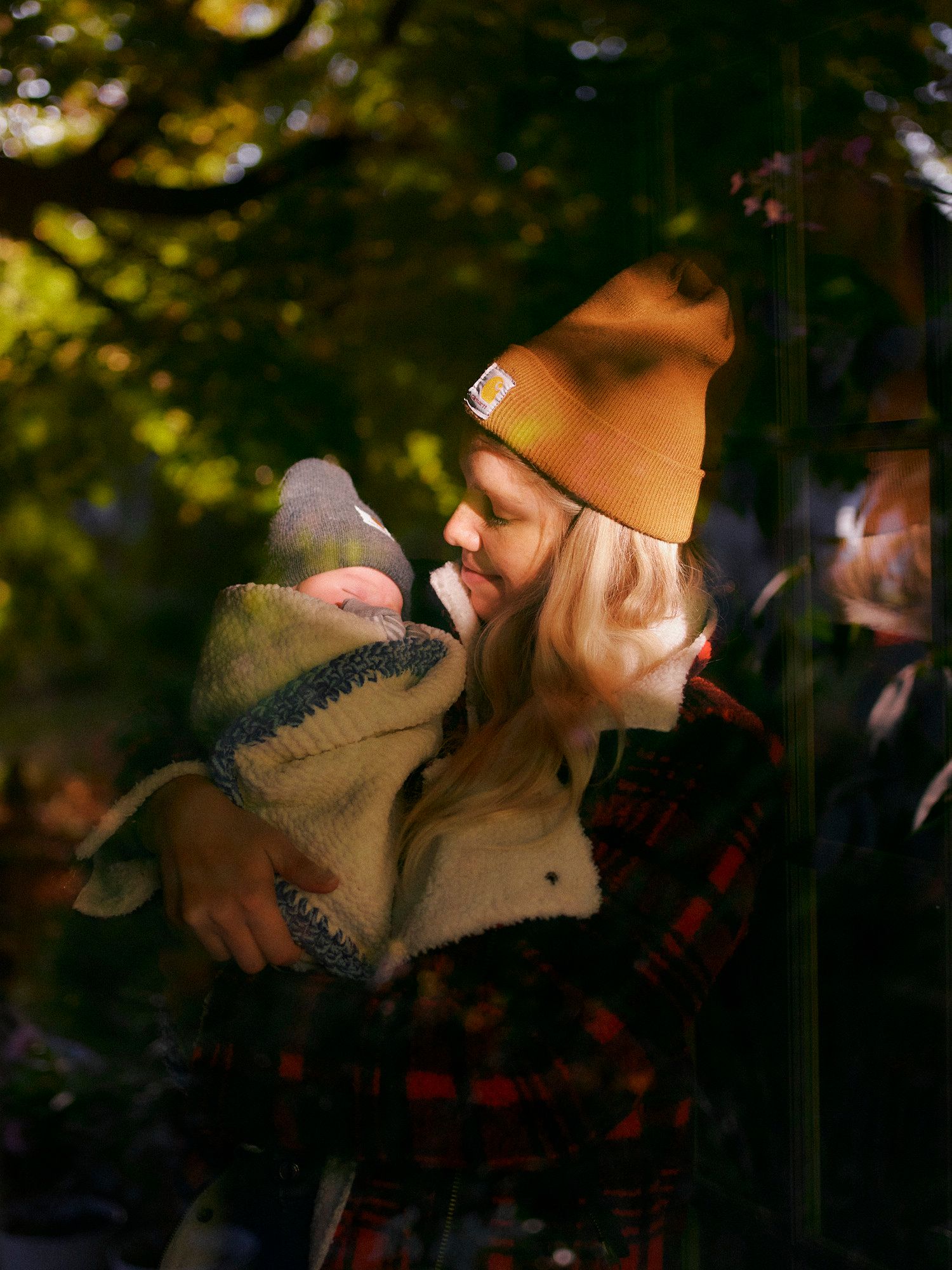 A person in a beanie and plaid shirt enjoying a peaceful autumn moment outdoors with blurred foliage in the background.