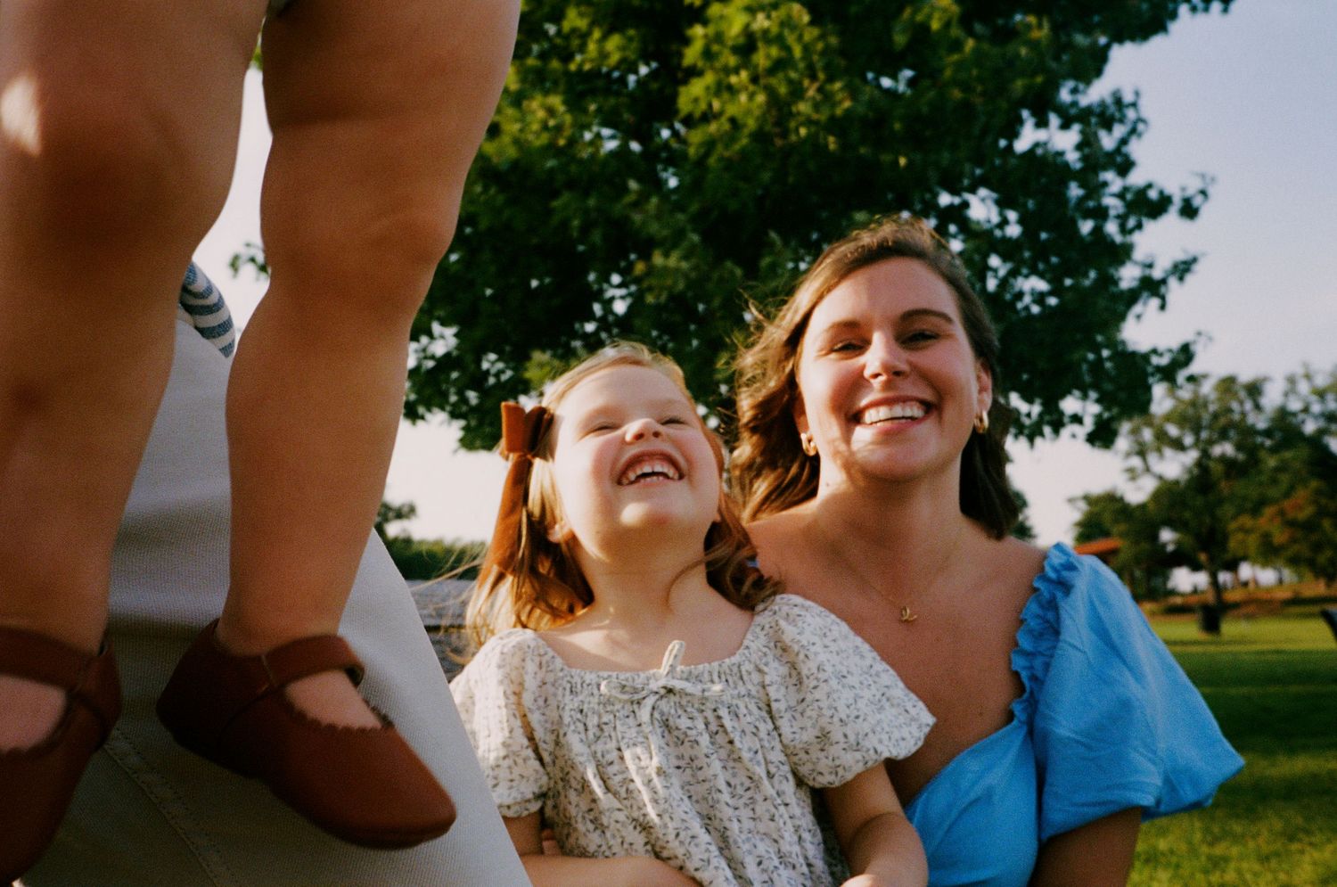Playful family moments captured from creative angles in a park setting.