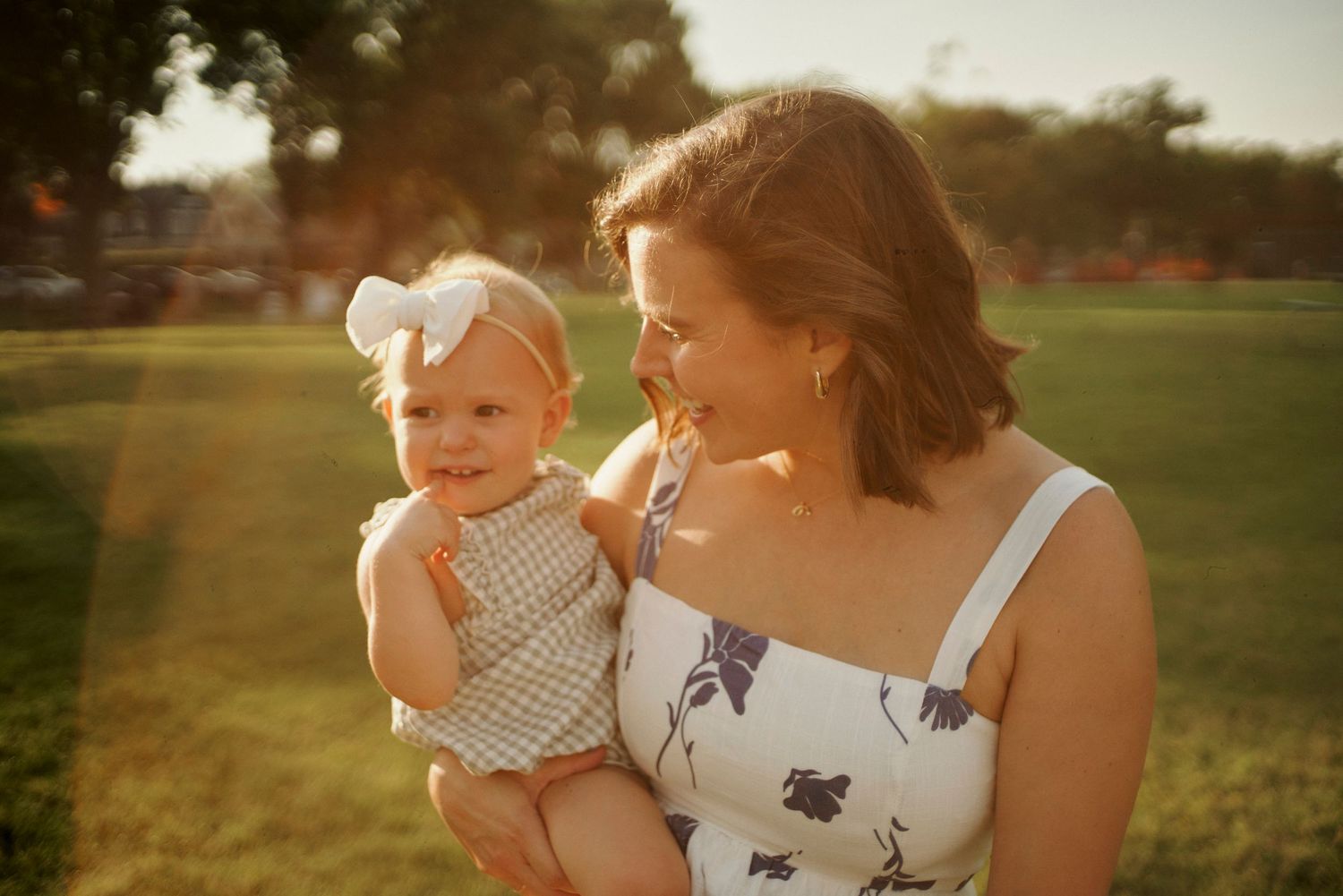 Candid family moments captured during sunset in a grassy park setting.