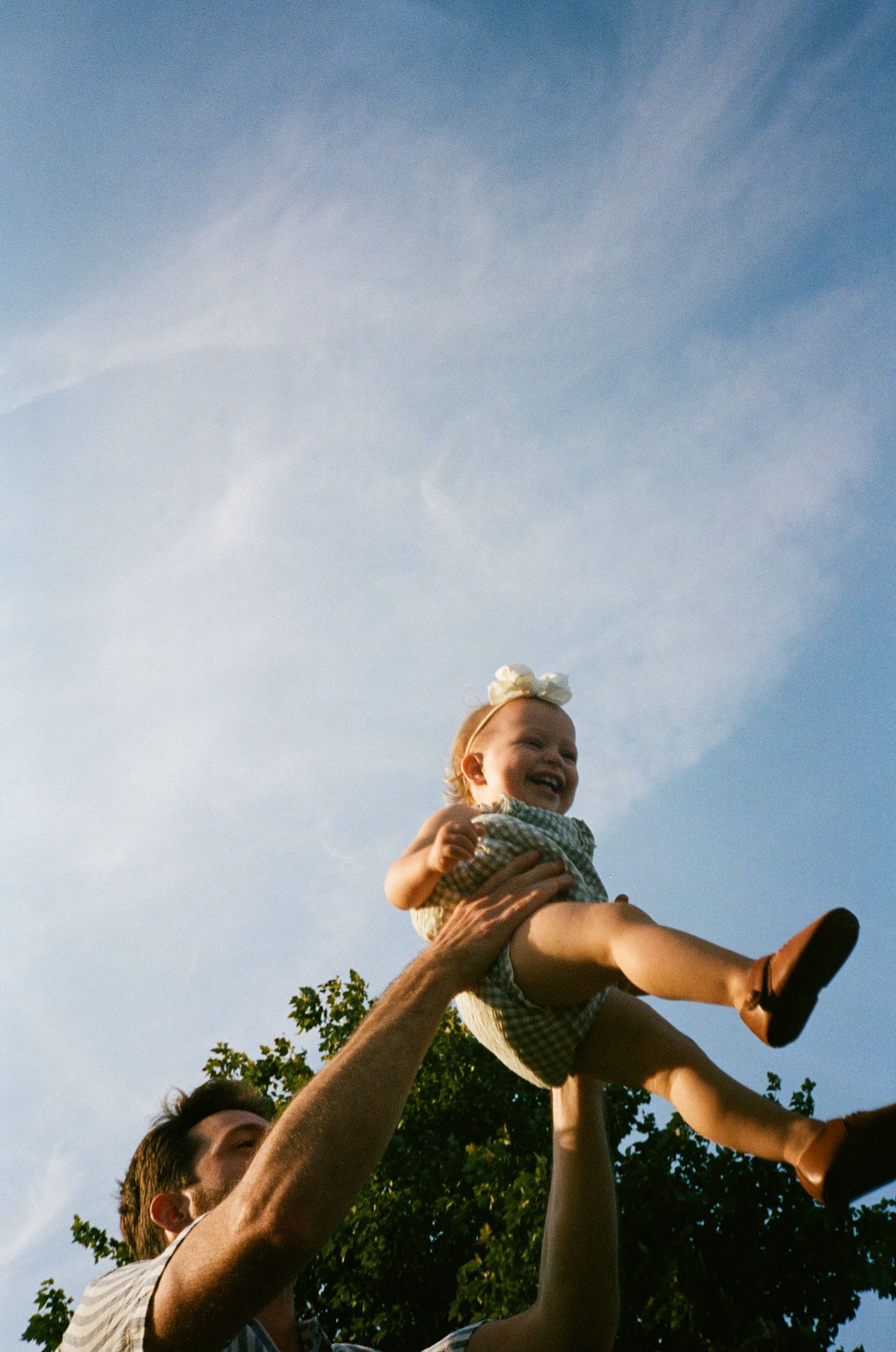 Silhouette of playful interactions against blue sky during outdoor photoshoot.