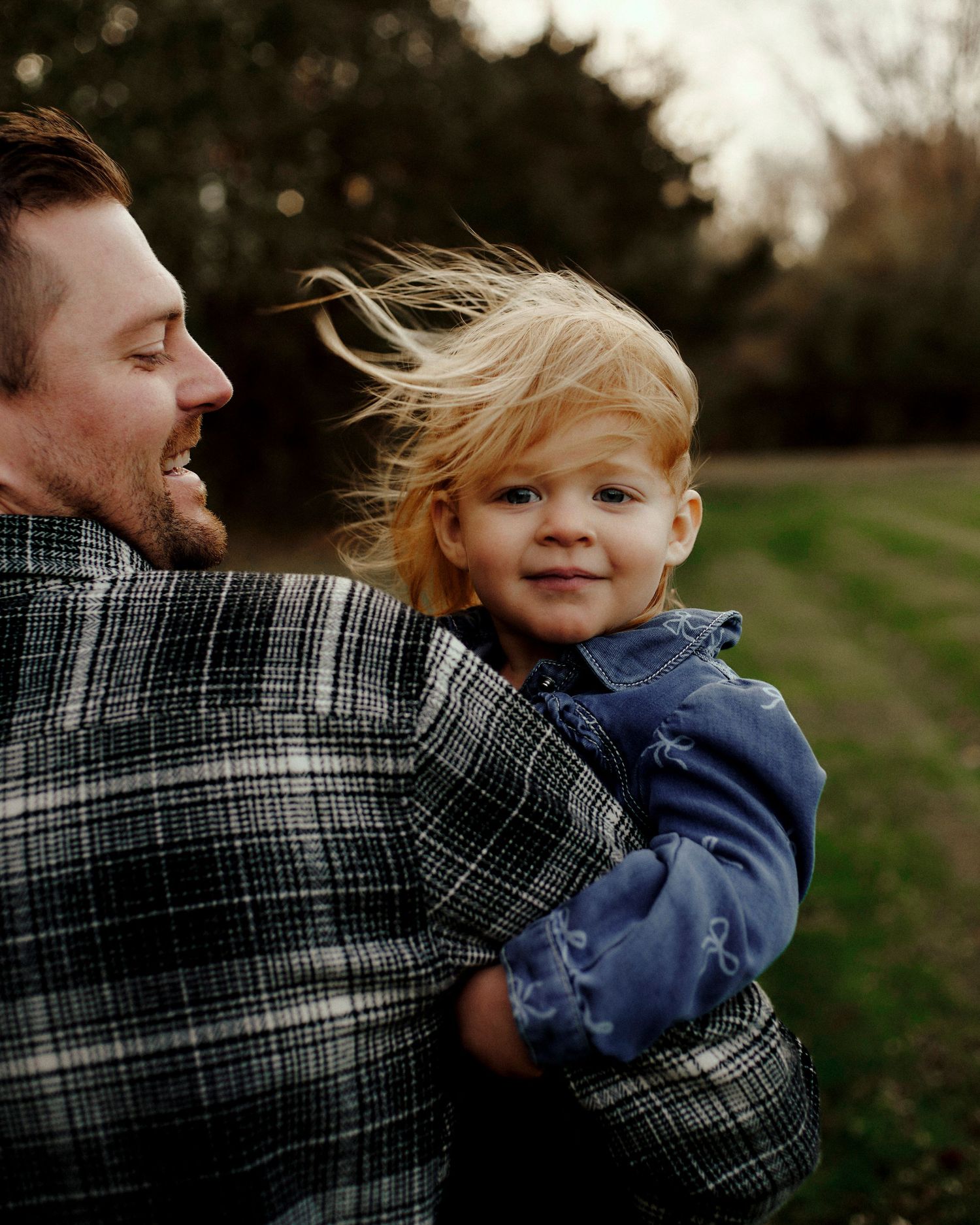 Candid family moment captured against blurred natural background at sunset.