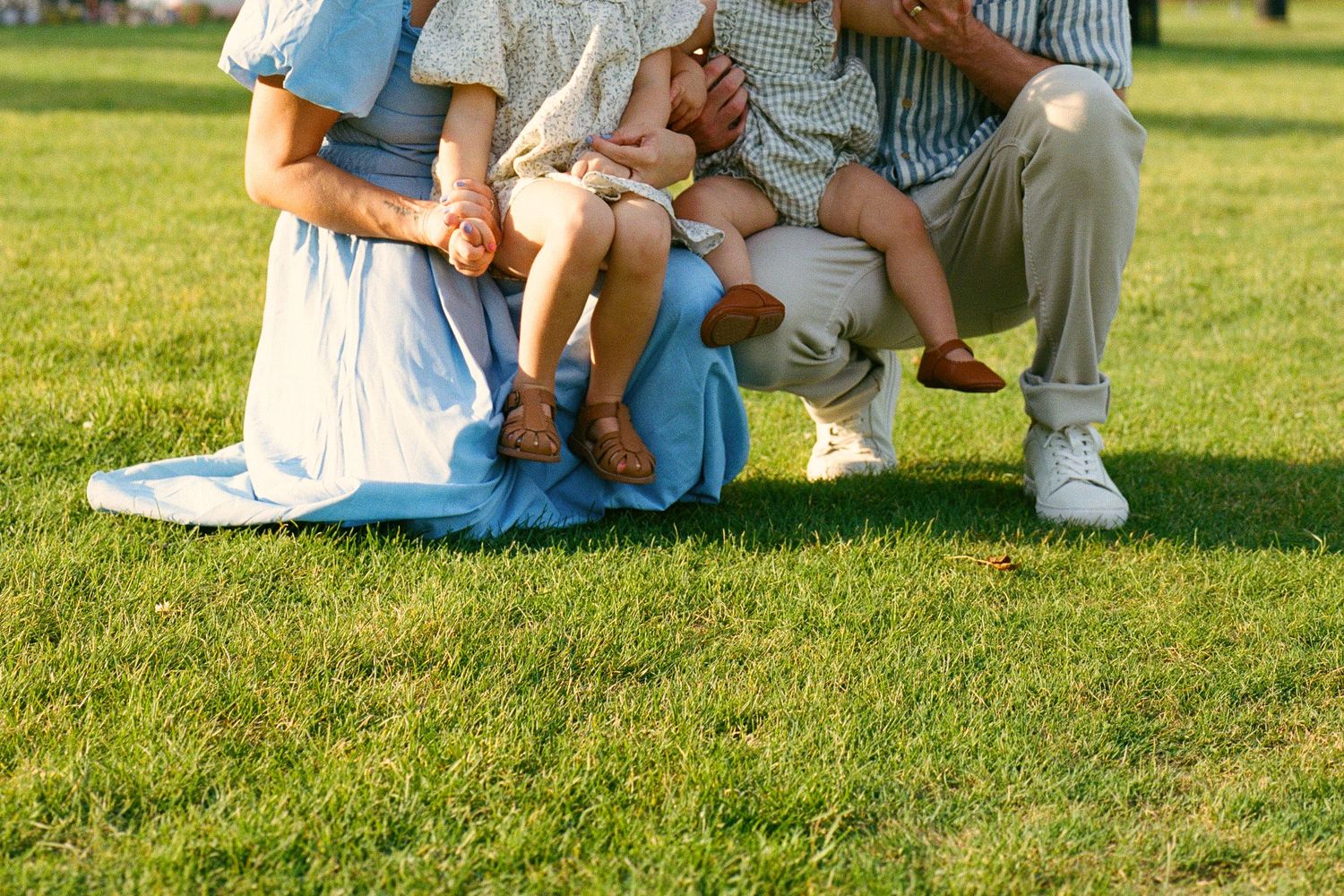 People sitting together on lush green grass in a park on a sunny summer day.