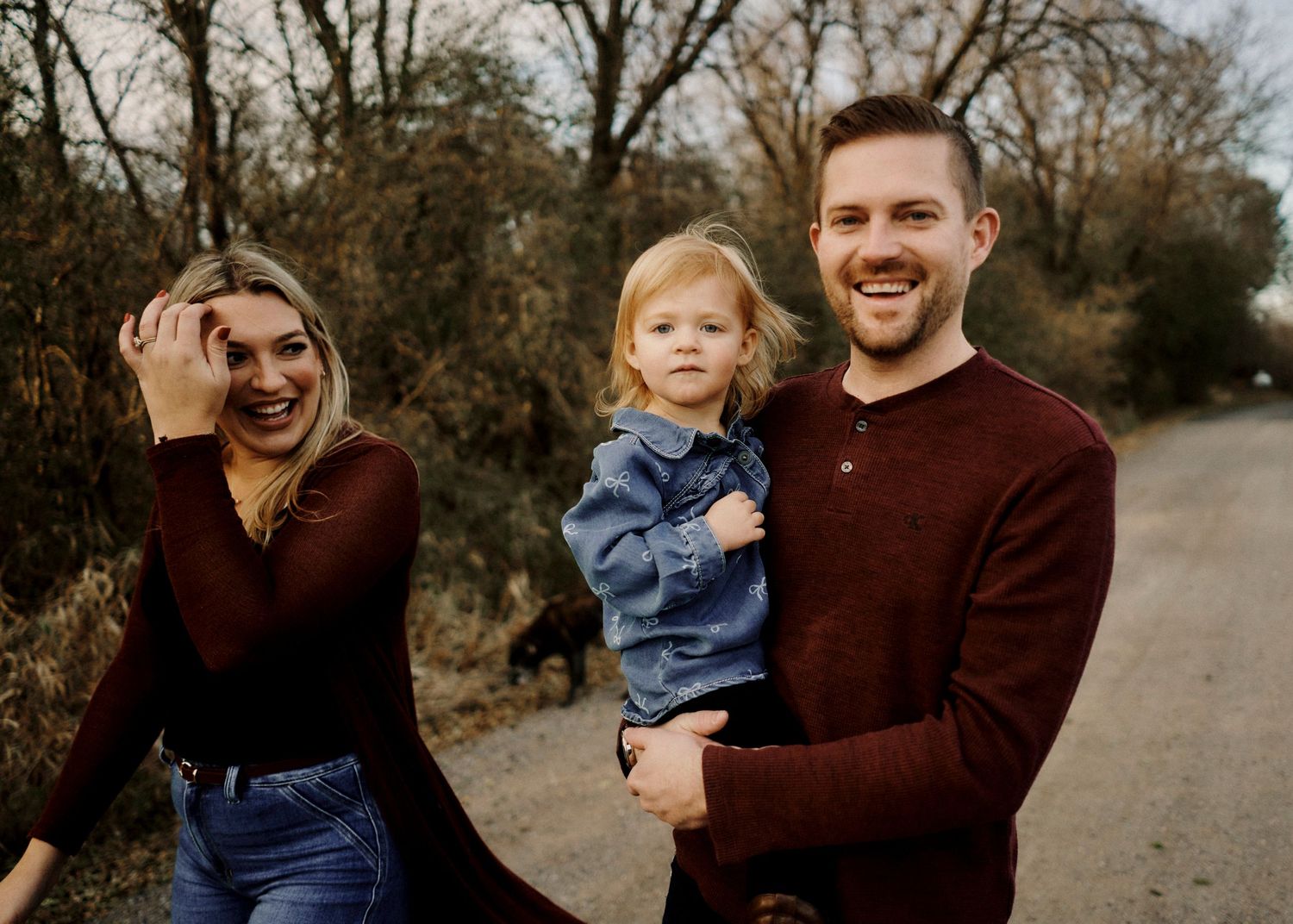 Candid family portrait session captured in a rustic outdoor setting during golden hour.