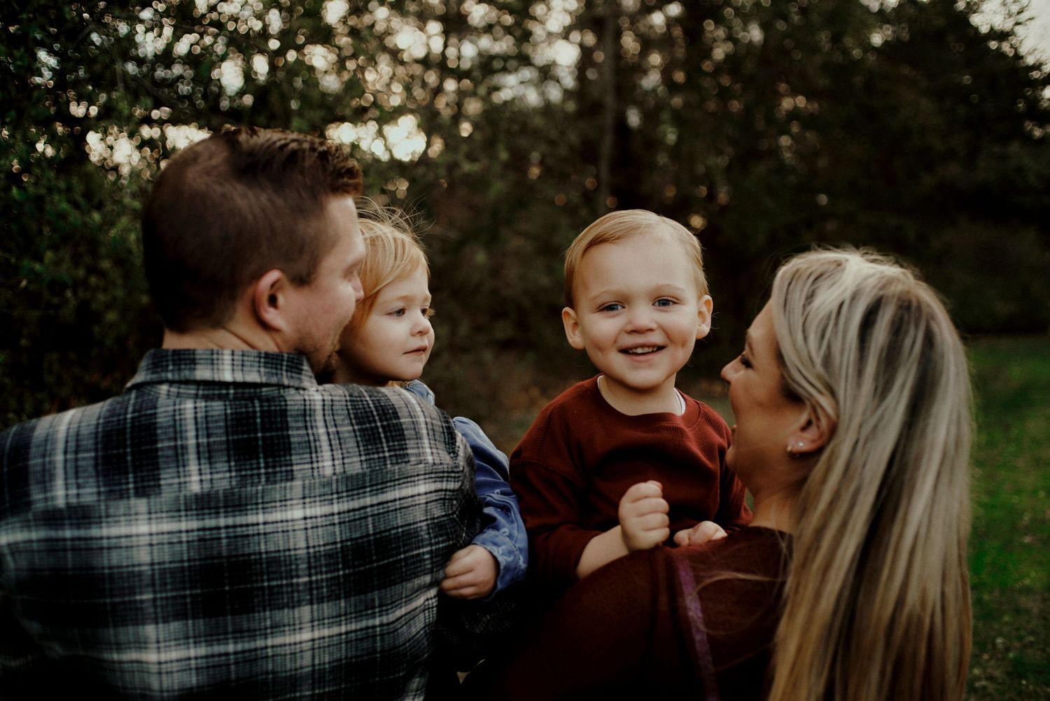 A family shares tender moments together outdoors during a photo session in a natural setting at sunset.