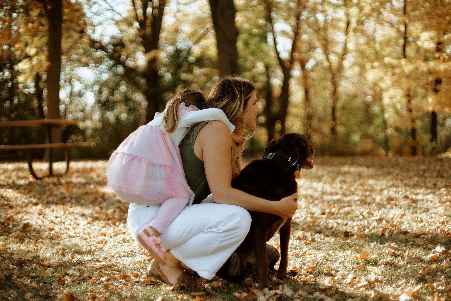 Candid moments captured in a wooded setting with autumn leaves on the ground.