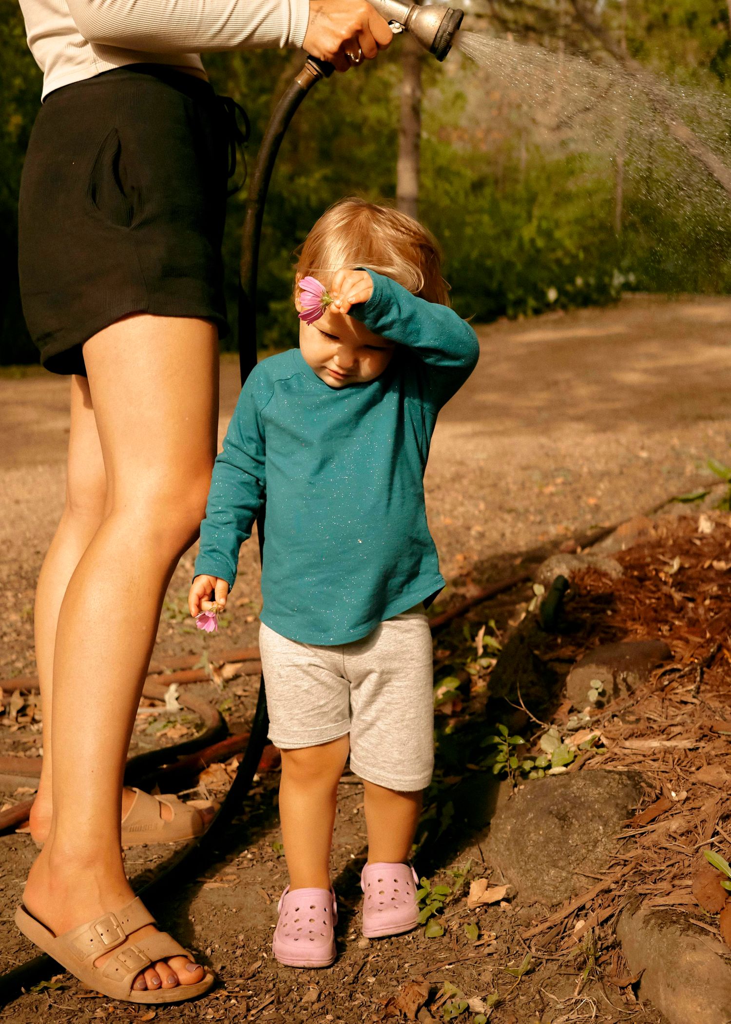 A series of photos showing adult feet in sandals walking alongside small pink shoes on a dirt path.