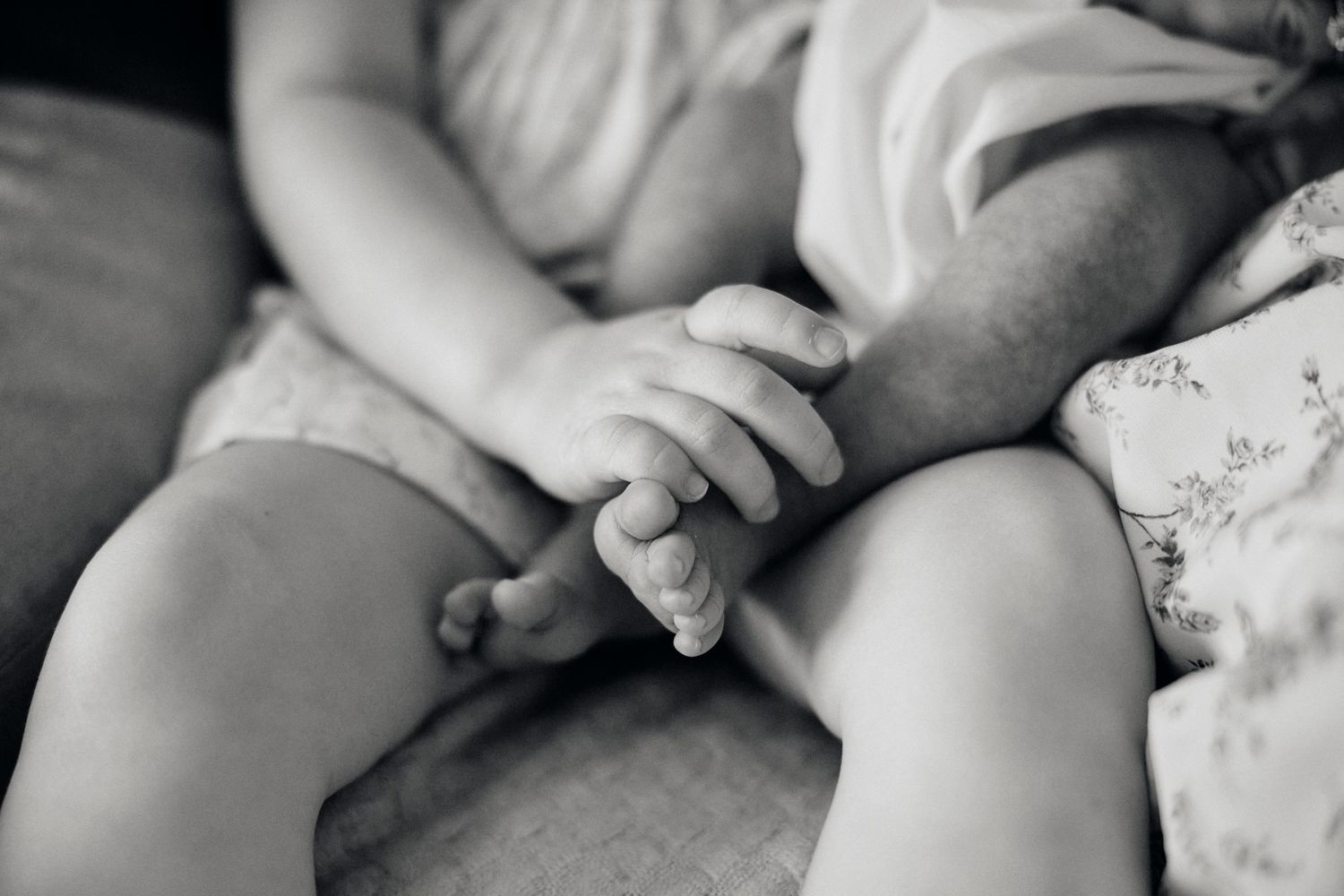 Black and white close-up of tiny infant hands resting on soft fabric.