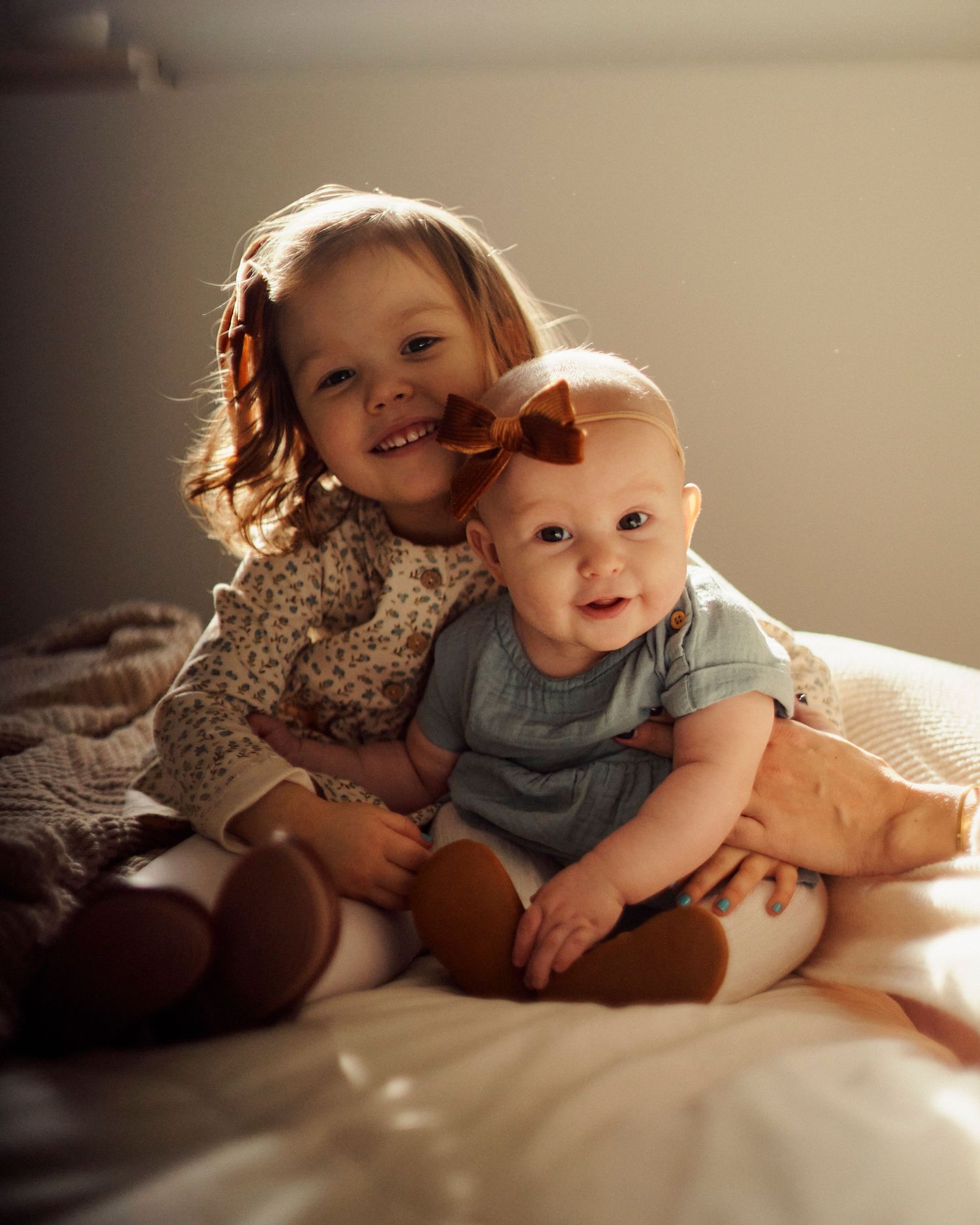 Two children cuddling together on a soft blanket in warm sunlight creating a cozy atmosphere.