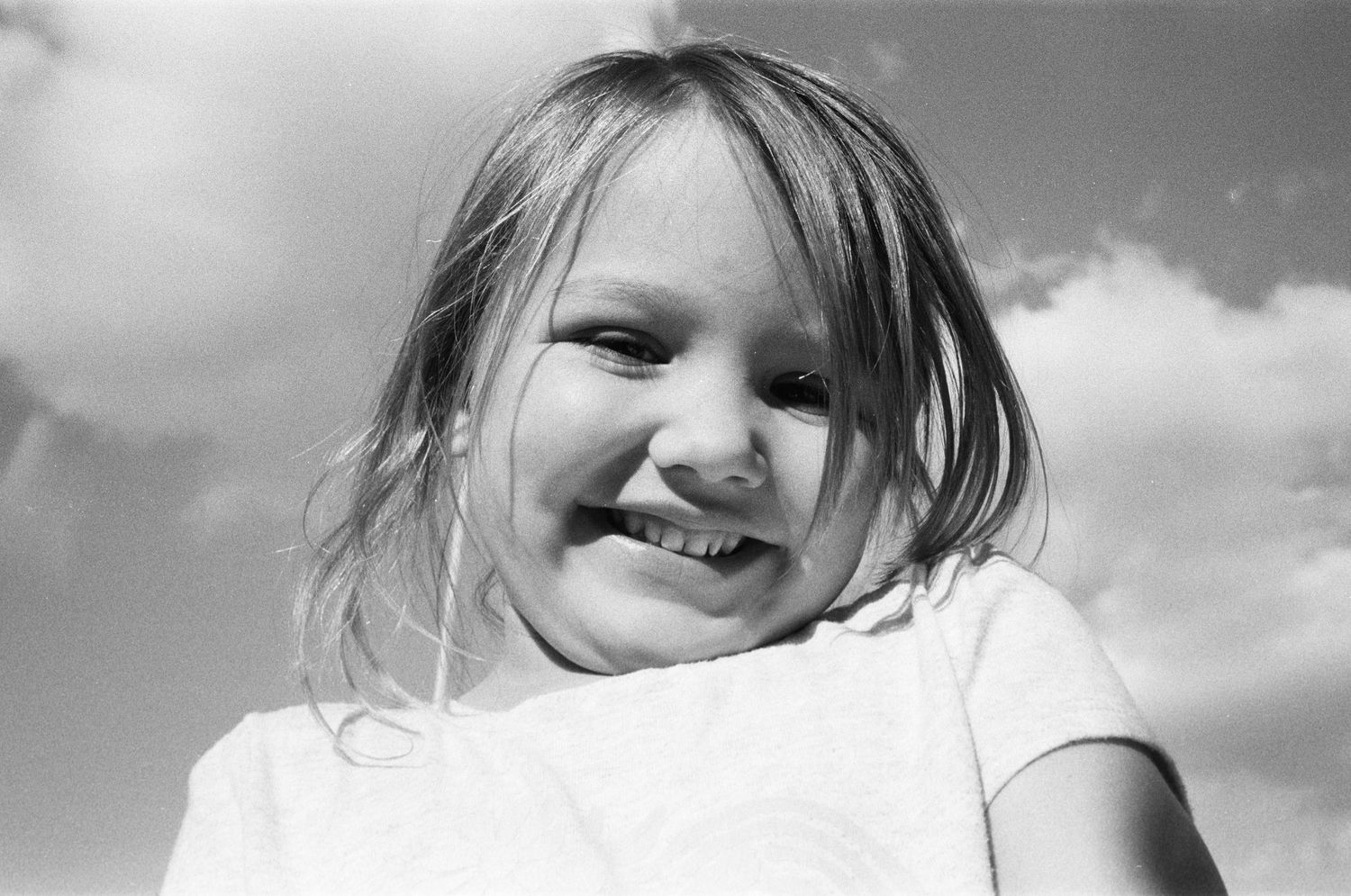 A black and white photo collage showing seven candid portraits of a person against various outdoor backgrounds.