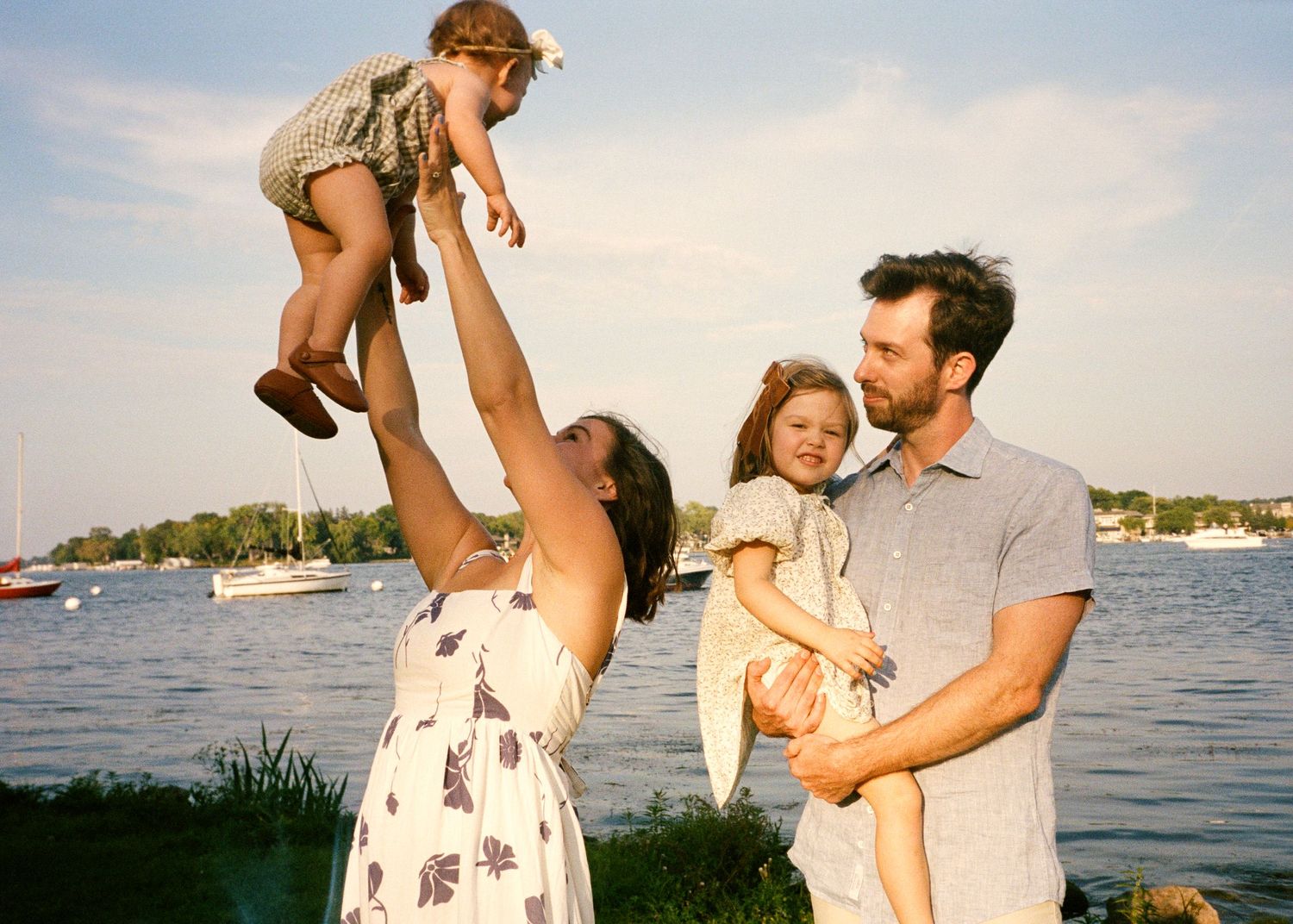 A family plays together near a waterfront during sunset.