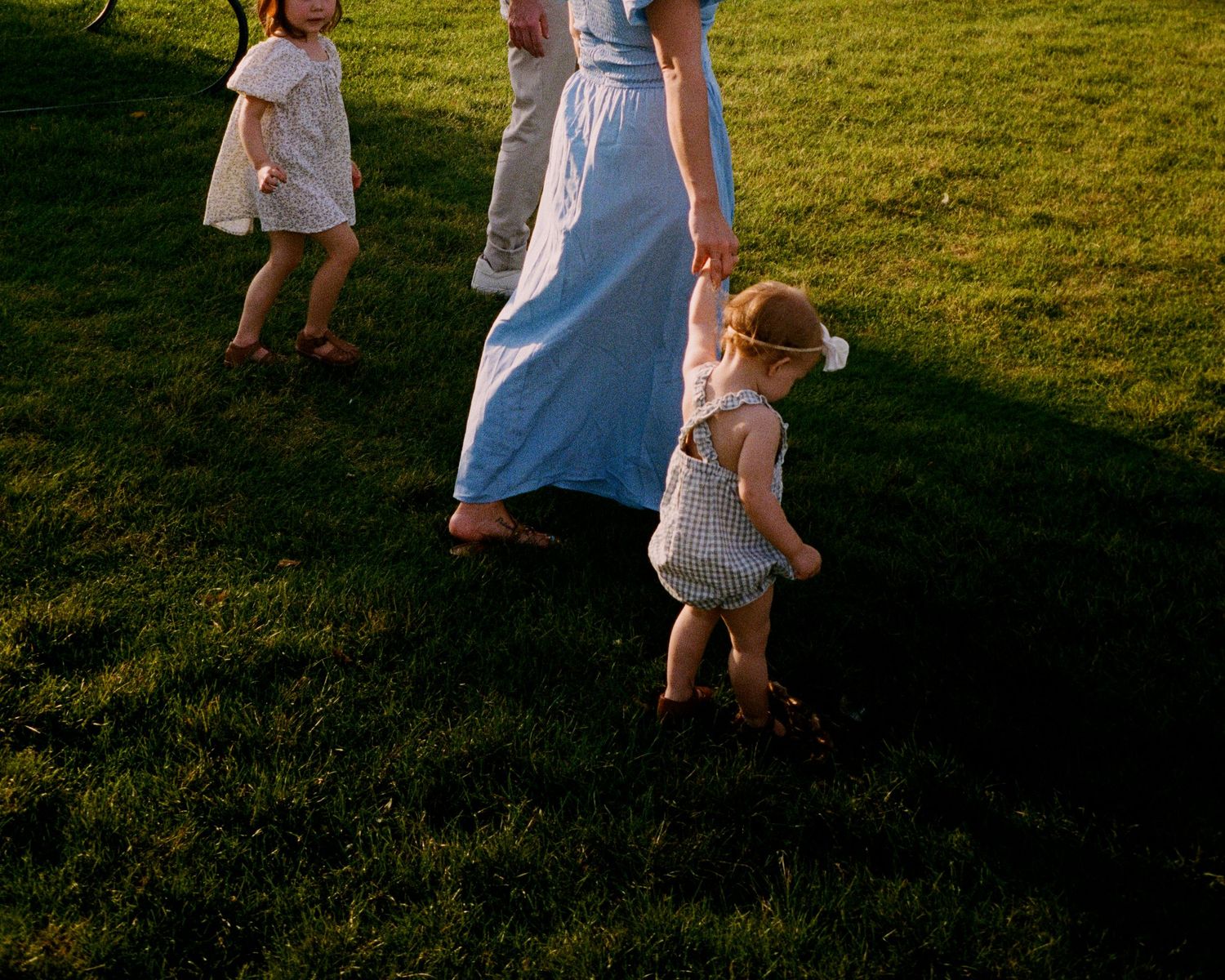 People playing and running together on a grassy field at sunset.