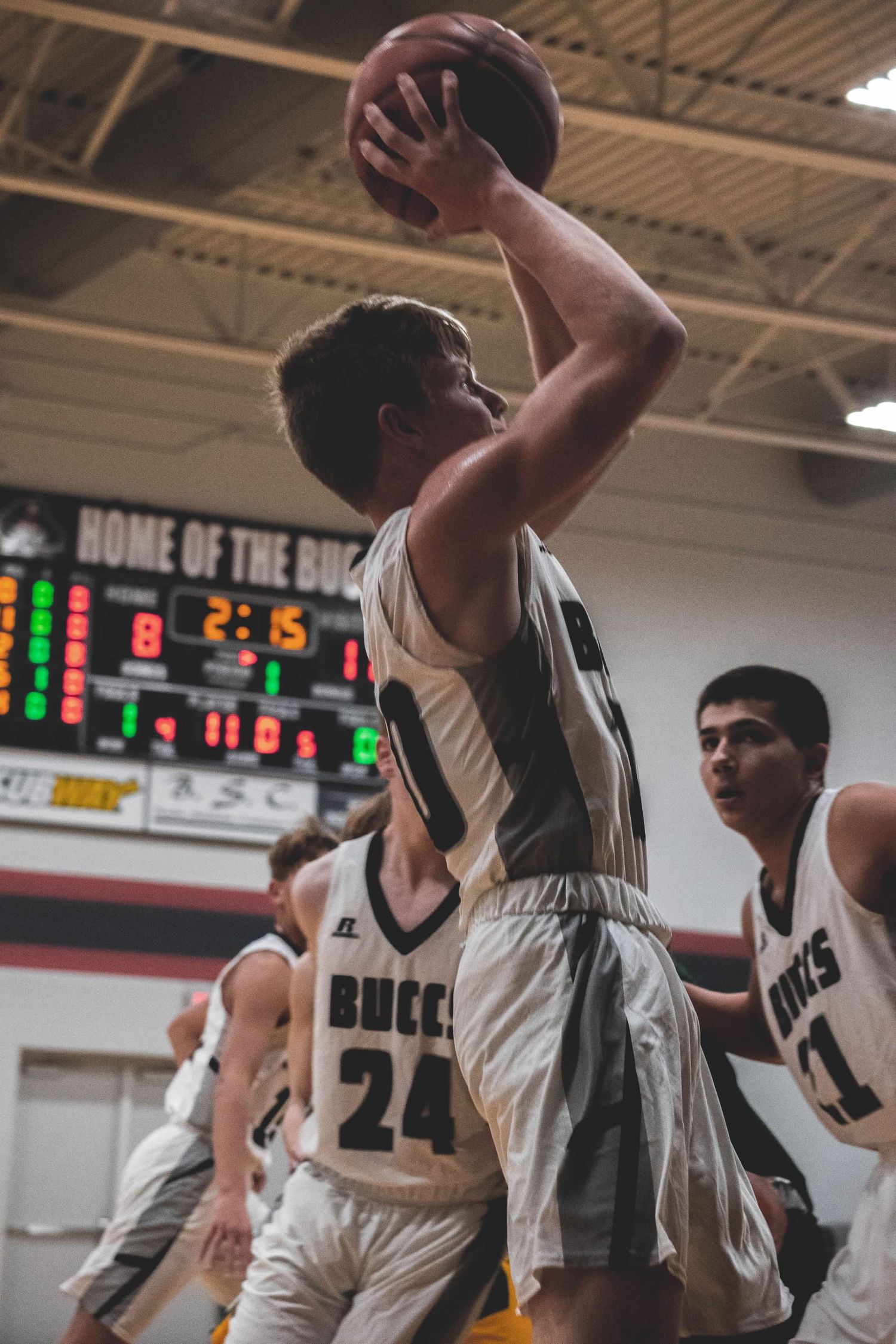 Basketball player in white jersey takes shot during intense game.