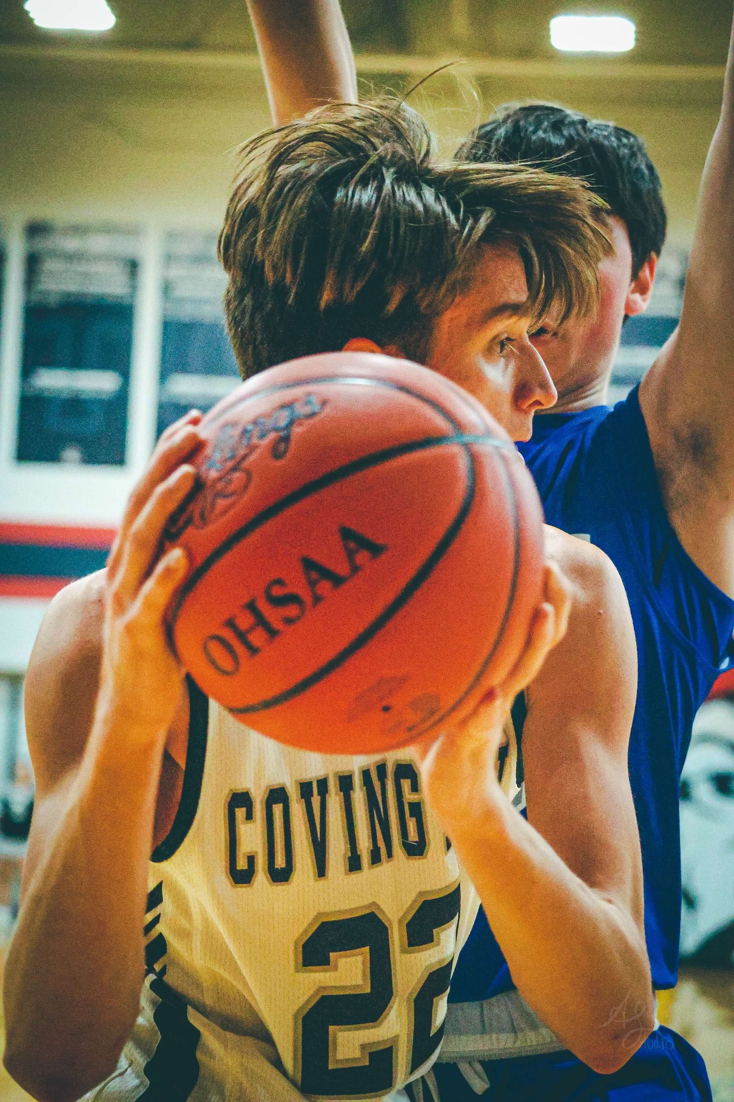 Basketball player in yellow jersey protects ball during intense game play.
