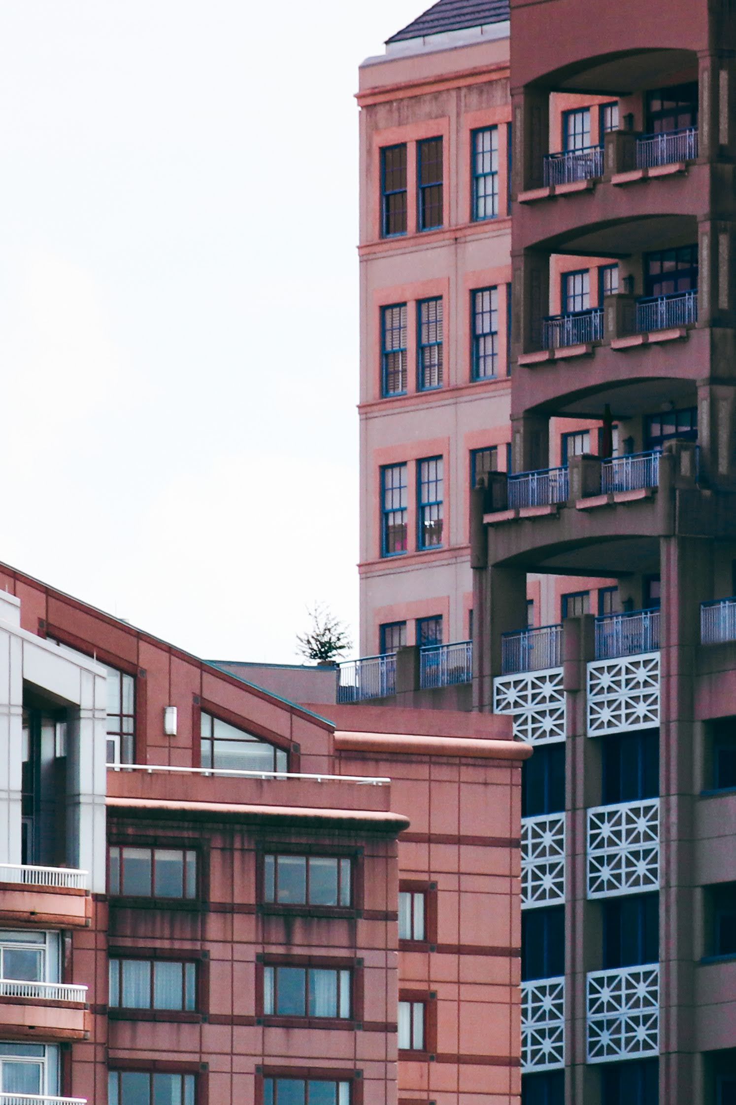 Modern apartment building exterior with distinctive balconies and terracotta colored walls.