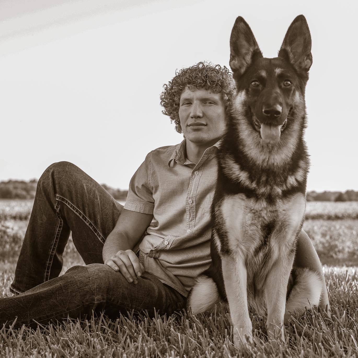 Black and white photo of a German Shepherd dog lying in the grass.