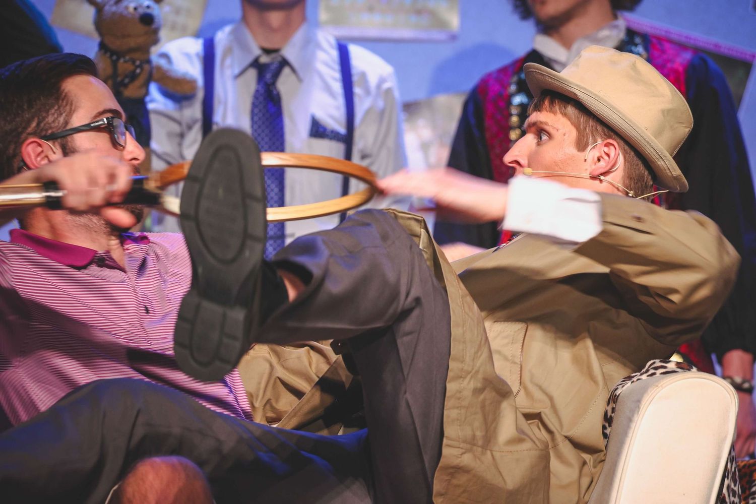 Group of performers acting dramatically on stage with theatrical gestures.