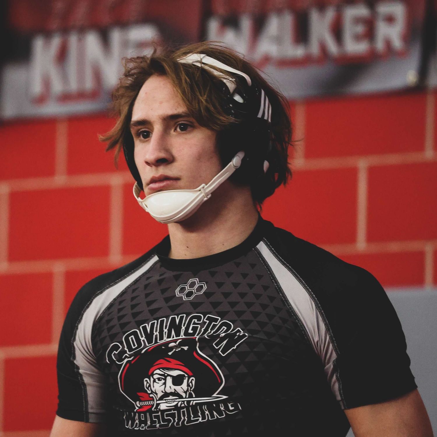 Wrestler wearing Covington team gear stands ready for competition.