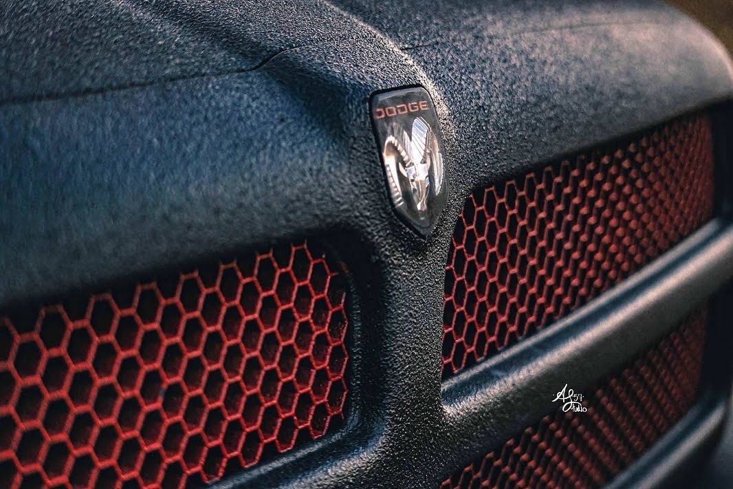 Close-up detail of red honeycomb mesh pattern on black automotive surface.