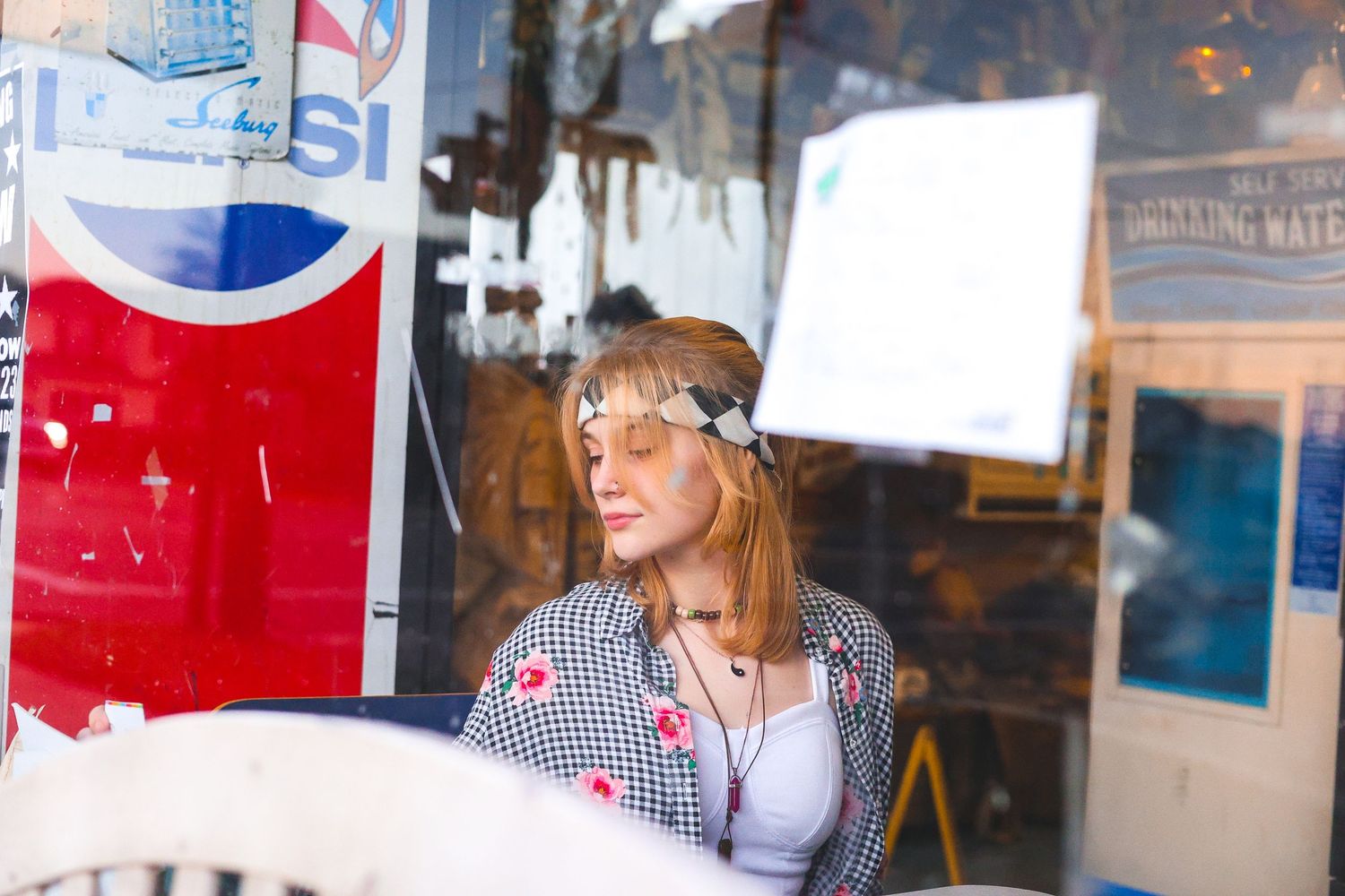 Woman in striped shirt with floral crown relaxes in retro-styled diner setting.