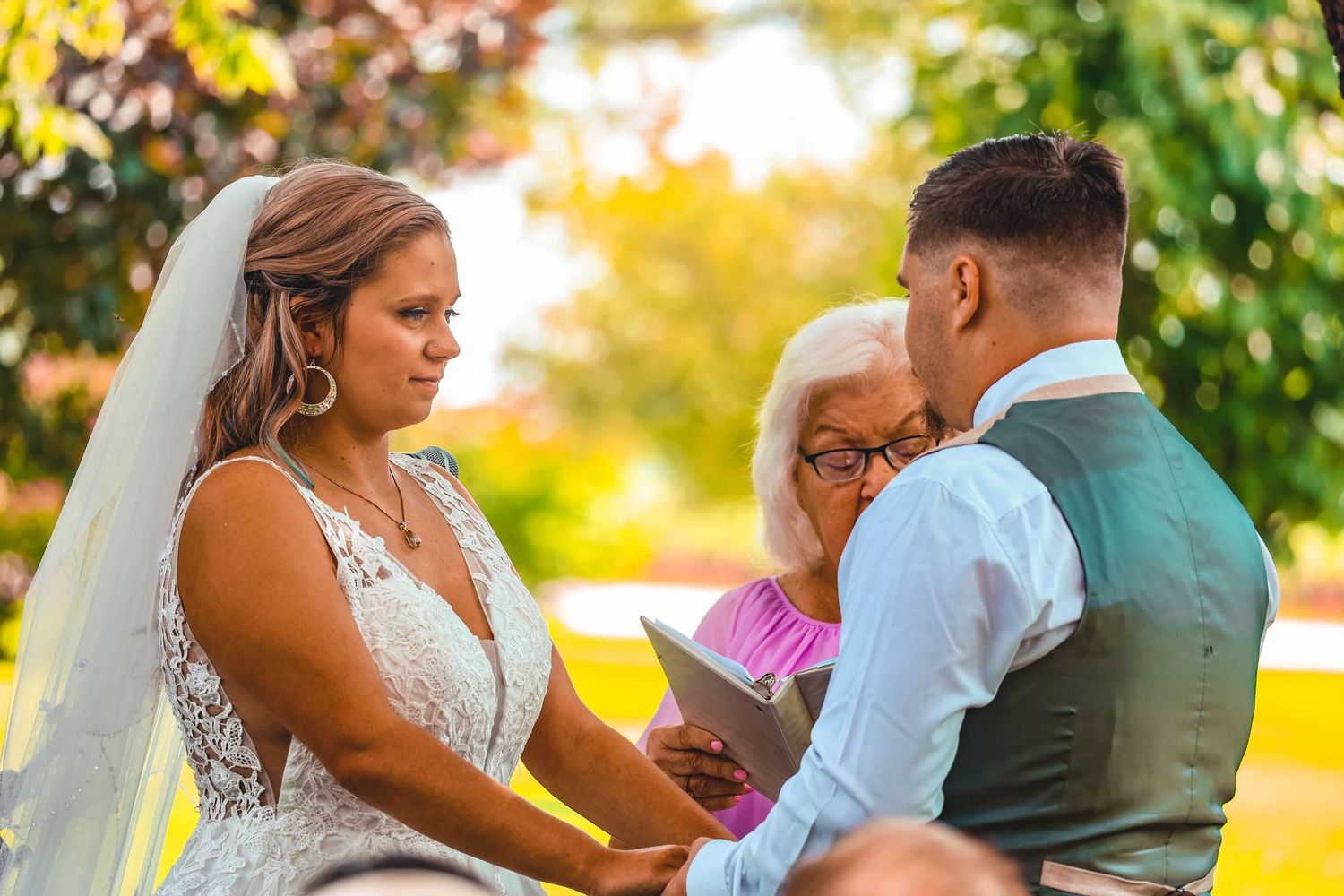 Couple holding hands in a romantic outdoor setting with golden sunlight filtering through autumn trees.