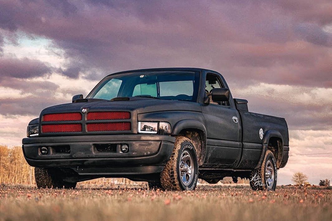 Classic cars lined up at sunset against a dramatic orange sky.