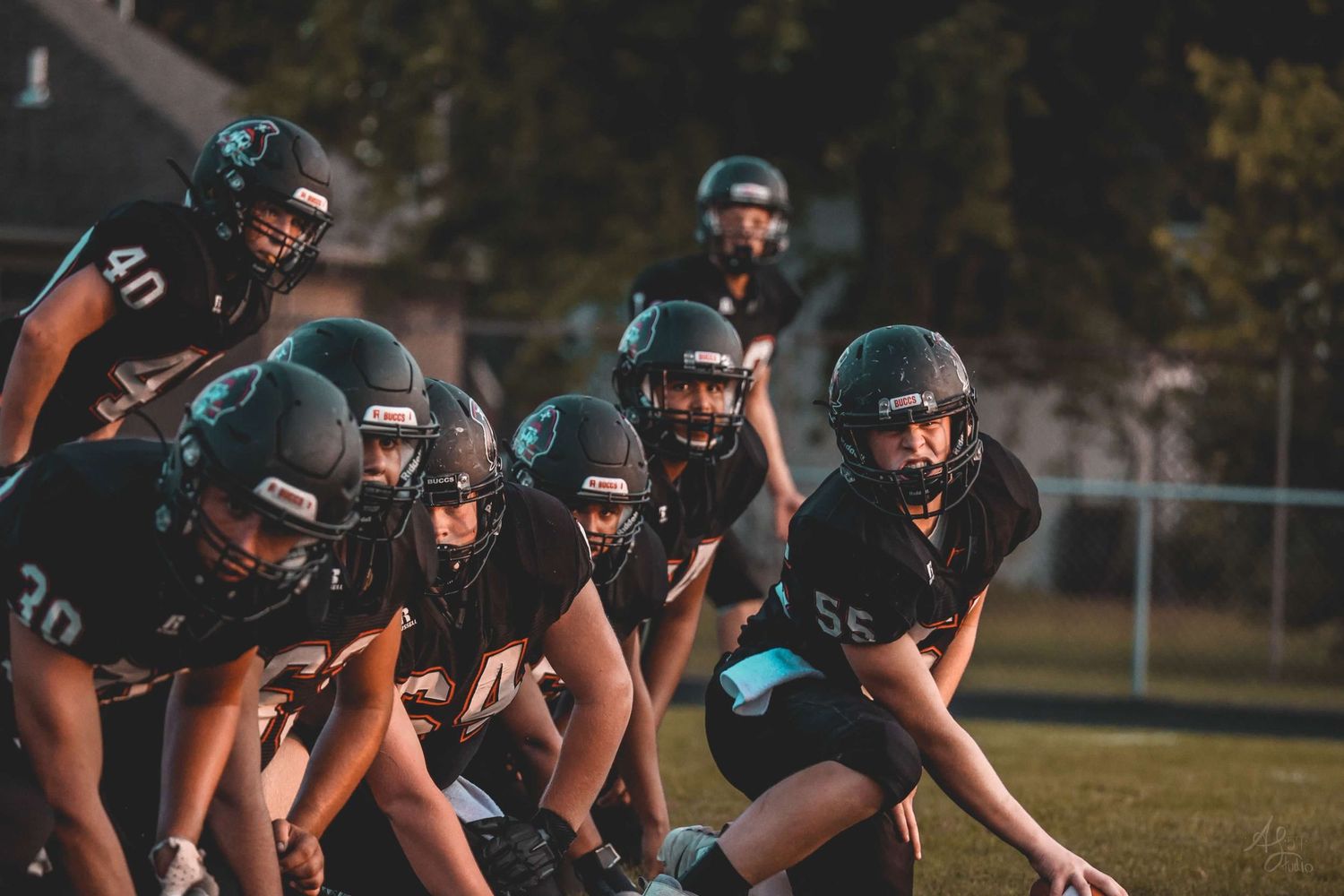 Football team lined up in formation during evening practice.