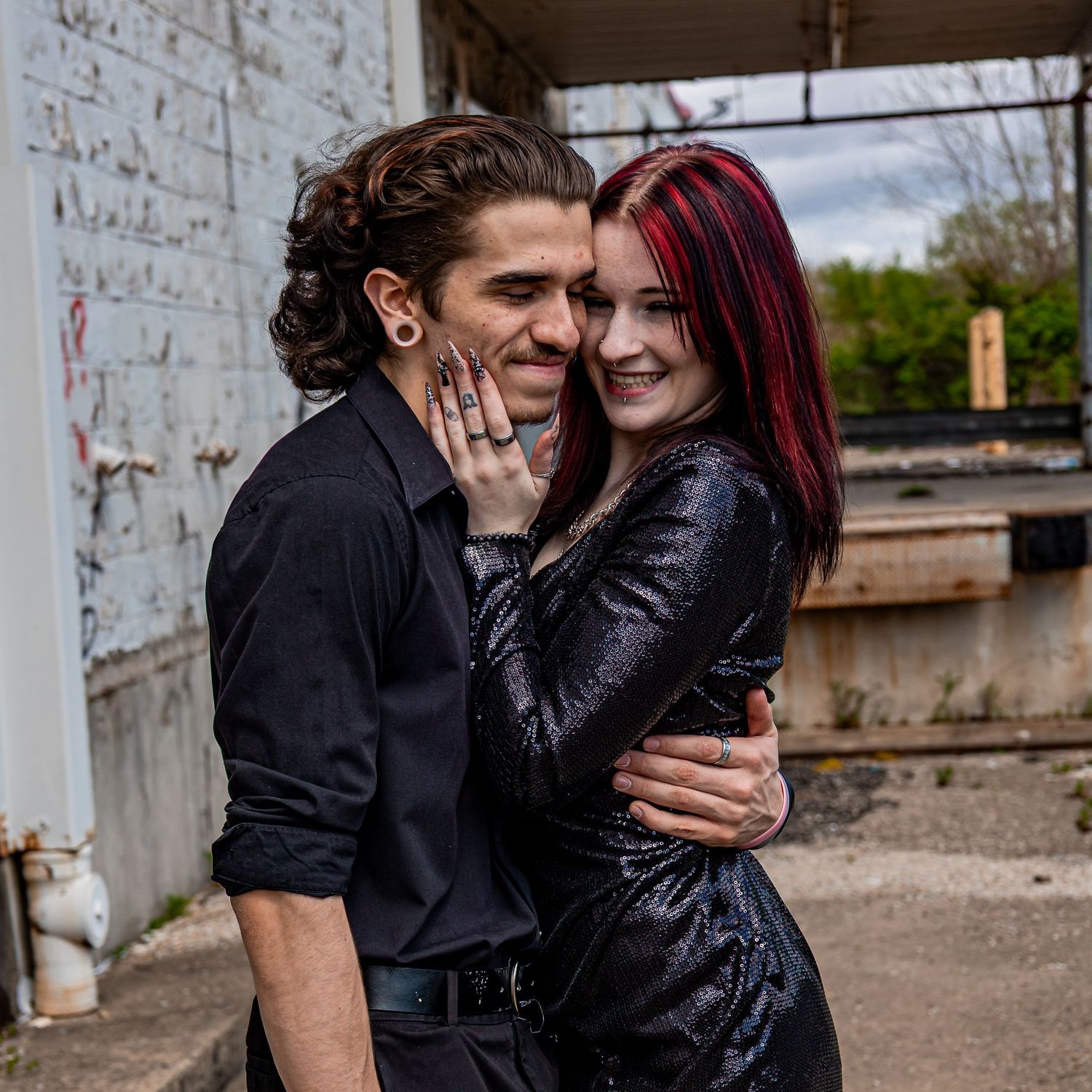 Romantic couple embracing against an industrial brick wall background.