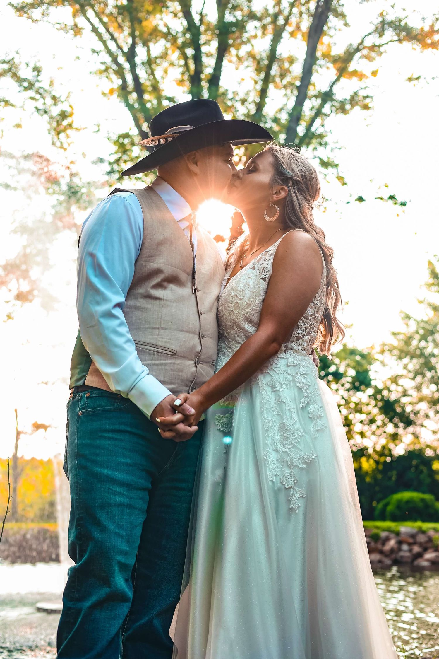 Couple in wedding attire sharing intimate moment in garden setting during golden hour.