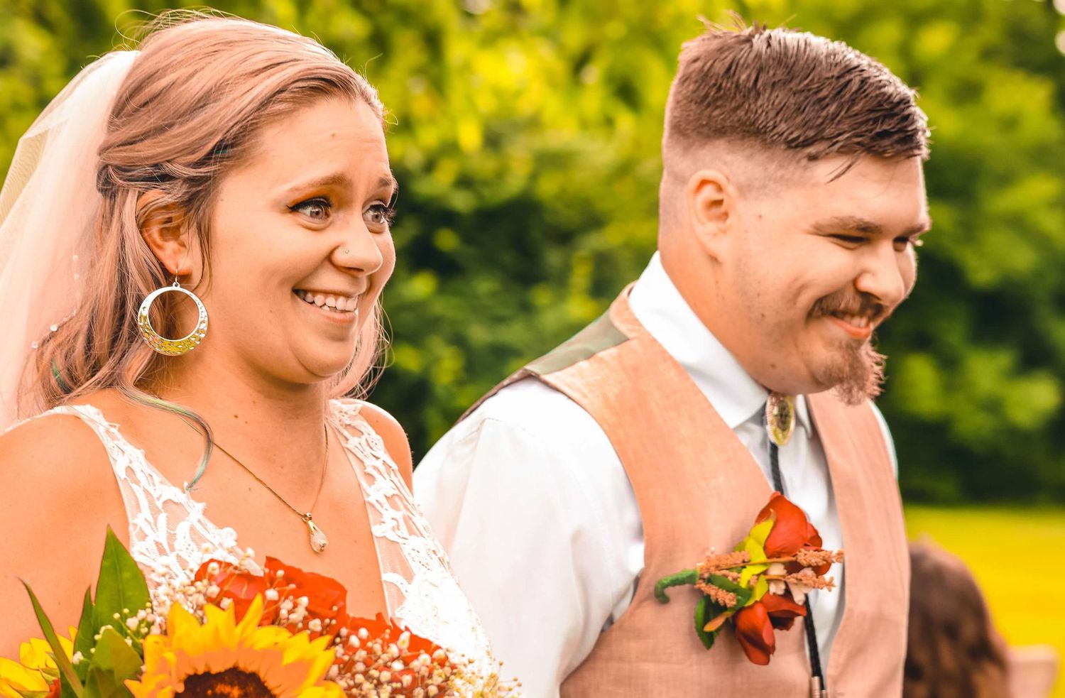 Wedding party members in formal attire with sunflowers against bright outdoor background.