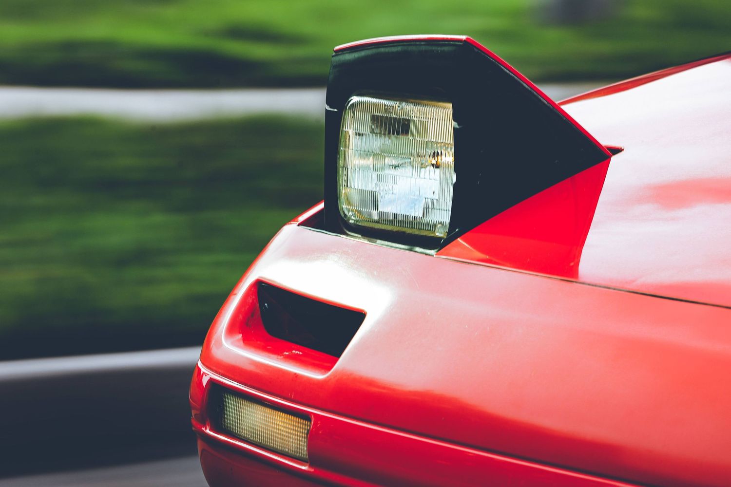 Front view details of a red sports car with distinctive headlights and grille.